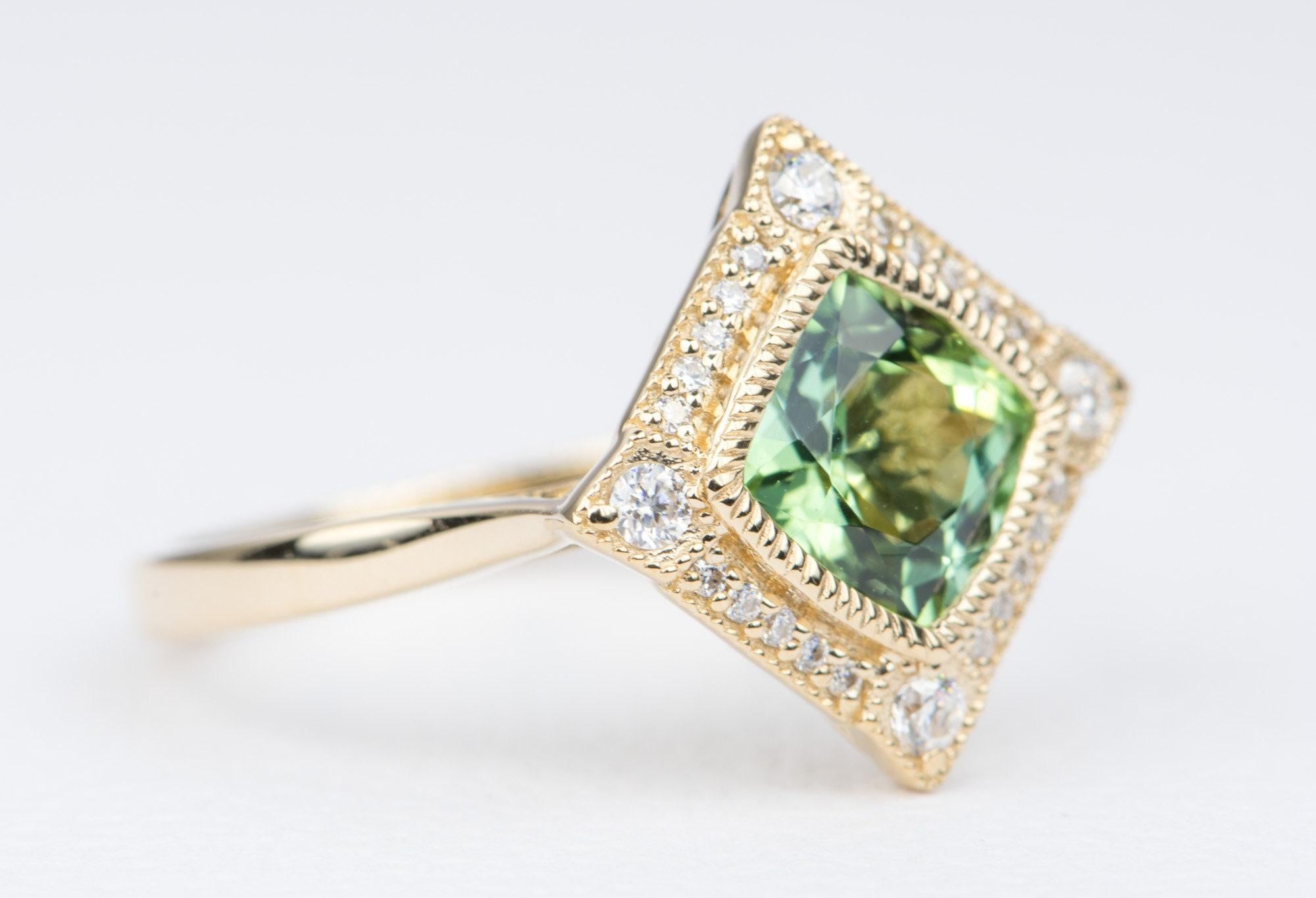 ♥ Solid 14K gold ring set with a beautiful green cushion cut tourmaline in the center and flanked by a halo of moissanite
♥ The center stone is bezel set with milgrain details. The halo also has an outer milgrain edge, for an overall