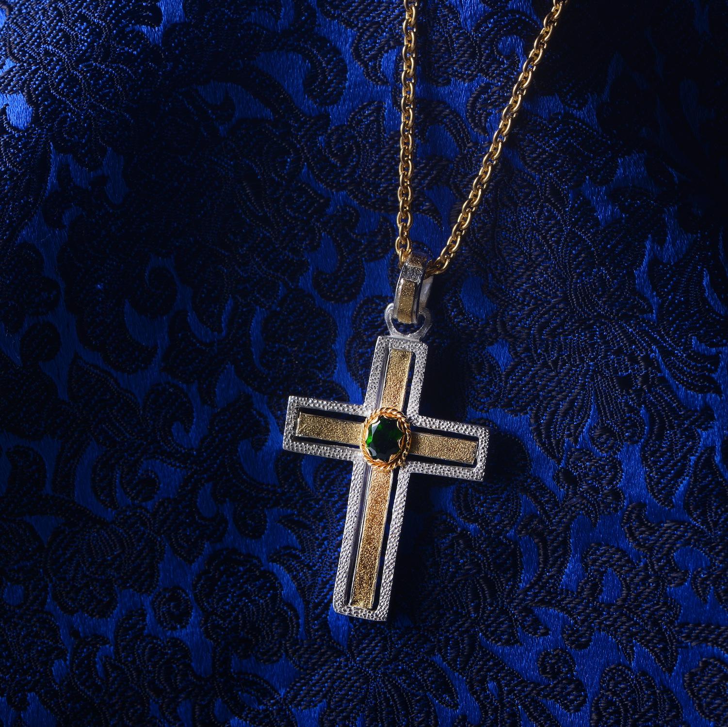 

This striking one-of-a-kind green tourmaline cross pendant has been handmade in our workshops. The pendant is made of lightly frosted sterling silver, overlaid with frosted 18k gold in the centre and on the hook of the pendant.  It is embedded
