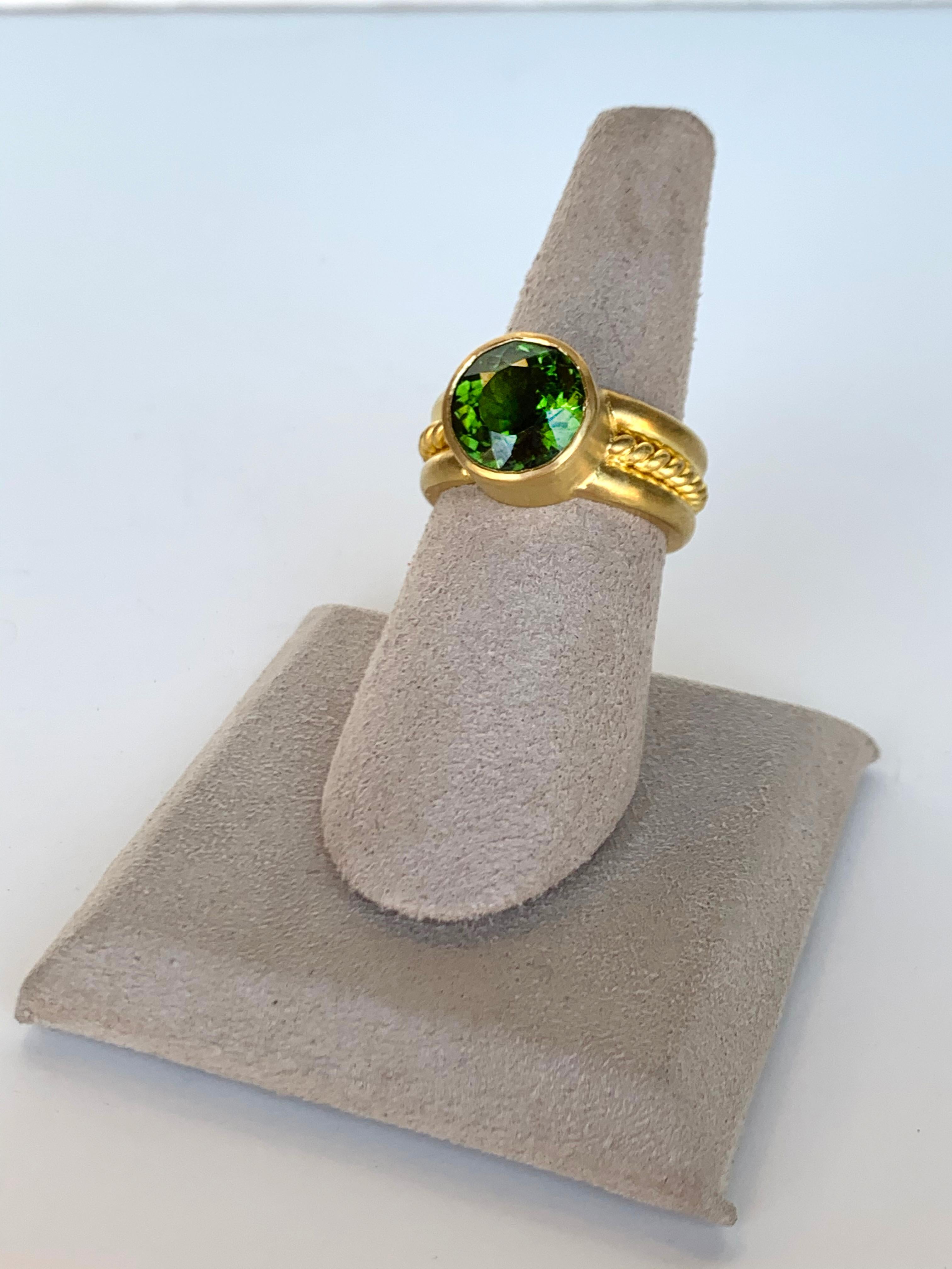 Inspired by ancient jewelry design, this vibrant faceted 4.25 carat green tourmaline is set in a 22 karat gold bezel. Thick 22 karat gold wire twists around the band. Entirely crafted by hand in New York.  Size 6.75.

