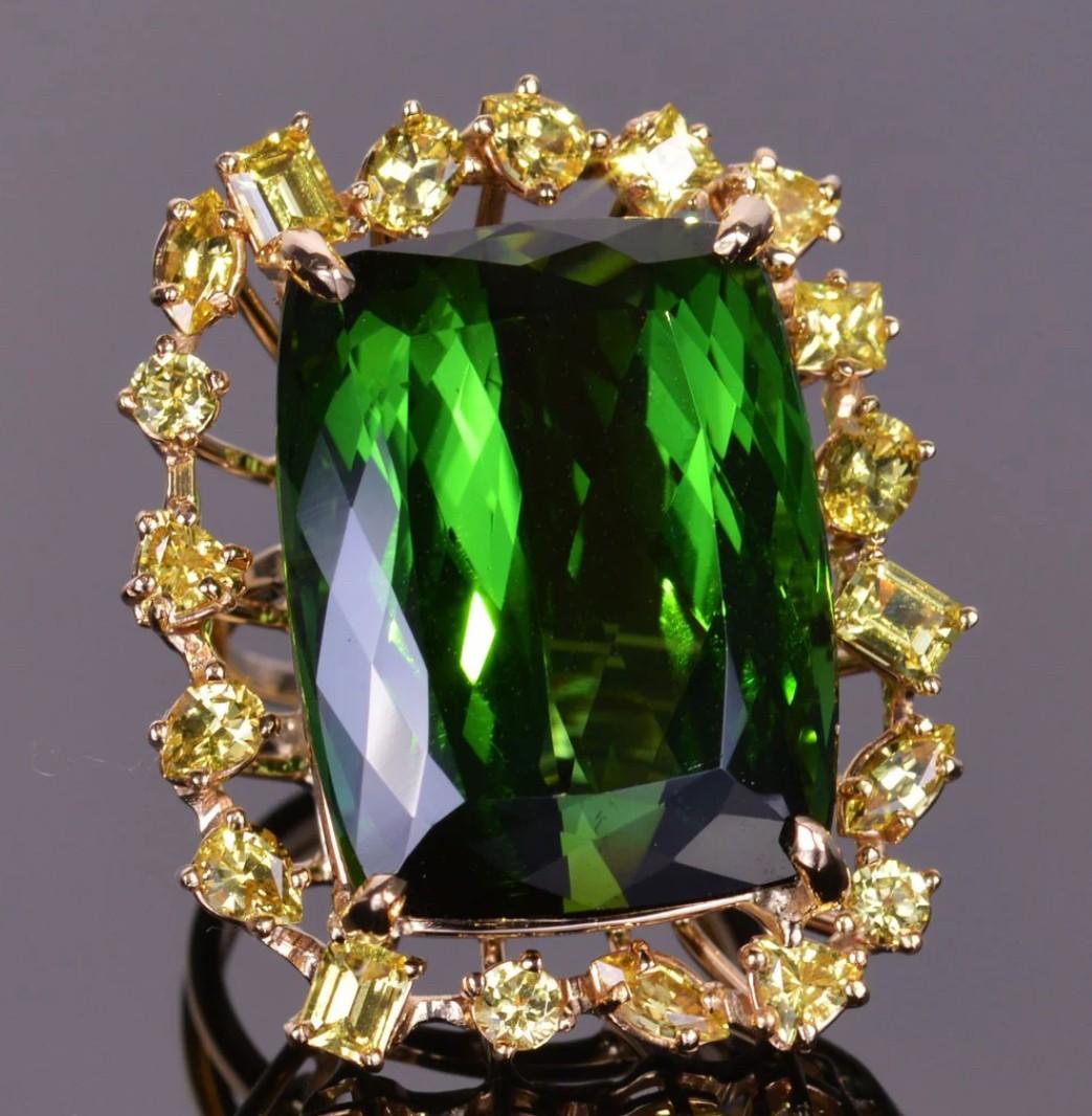 This massive and gorgeous 43.61 carat green tourmaline is surrounded by 4.57 carats of mixed cut canary yellow sapphires all hand fabricated in 18k yellow gold. The dimensions of the ring are 33.2mm x 28.5mm. Ring size is a 7.

Additional sizes