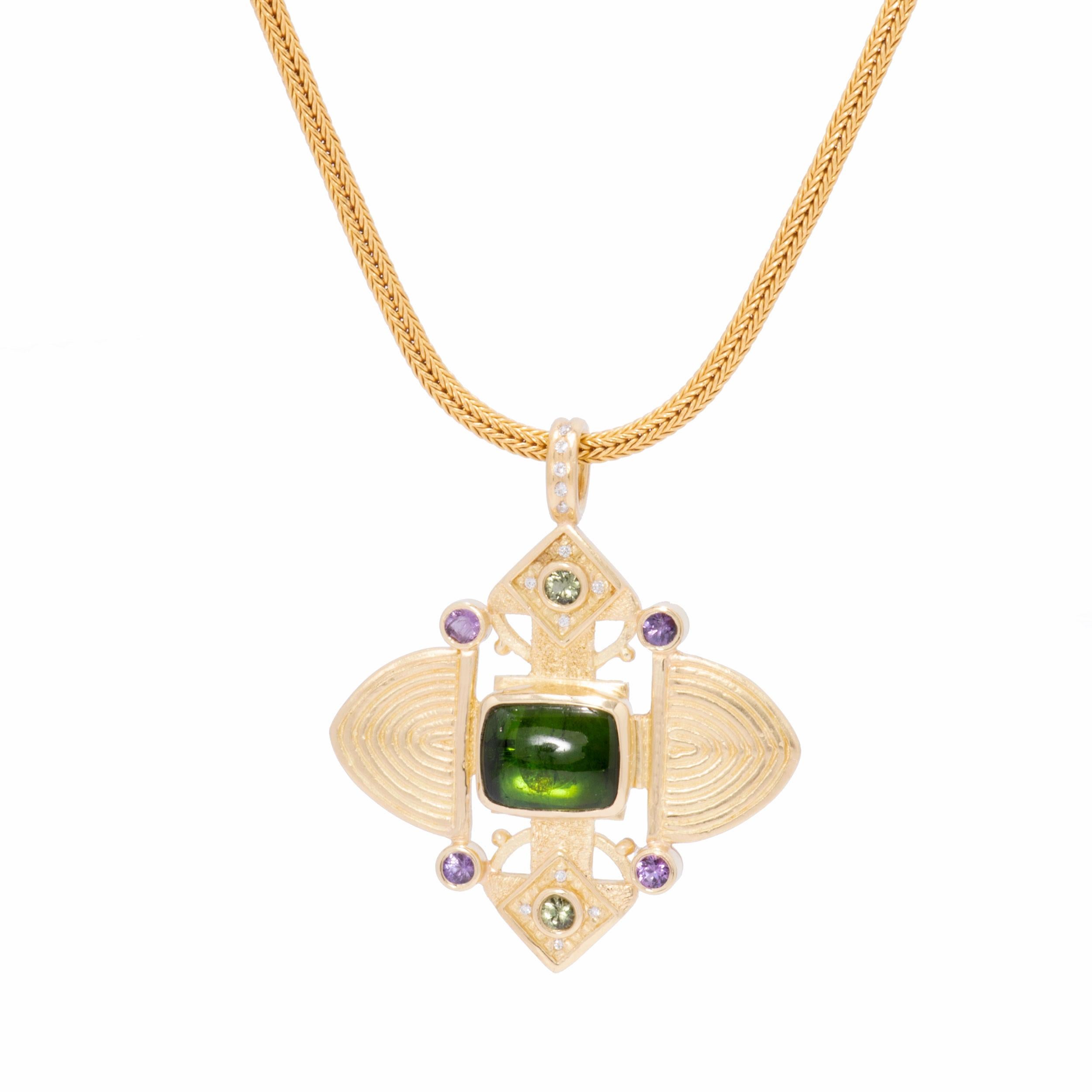 A vibrant moss green tourmaline cabochon 6.05cts is the focal point of this lavish 18k gold Ashanti Cross Pendant. Heathery purple sapphires and lettuce green sapphires .78ctw. harmonize to provide a finely balanced treasure. White diamonds .14ctw