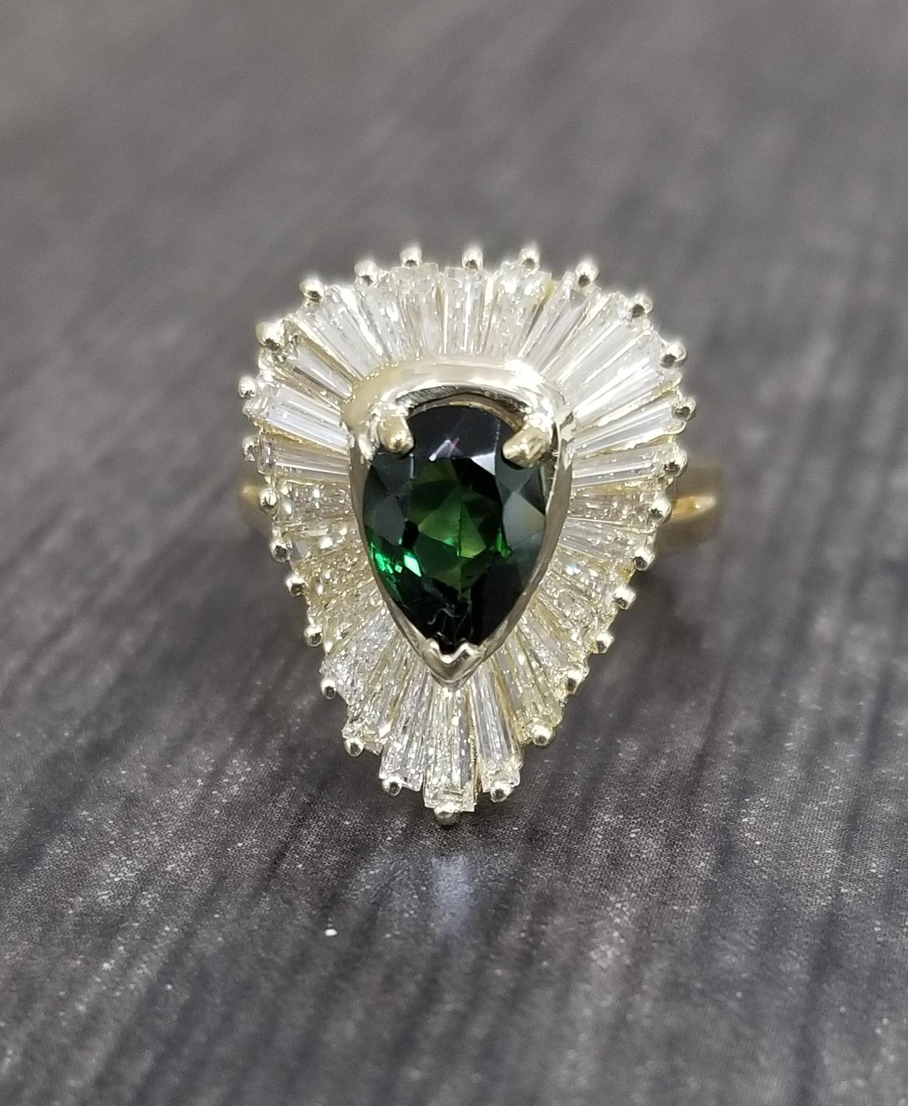 18k yellow gold ladies diamond baguette cocktail ring containing 1 pear shape green tourmaline weighing 1.09cts. and 28 baguette cut diamonds of very fine quality weighing 1.75cts. set in a 
