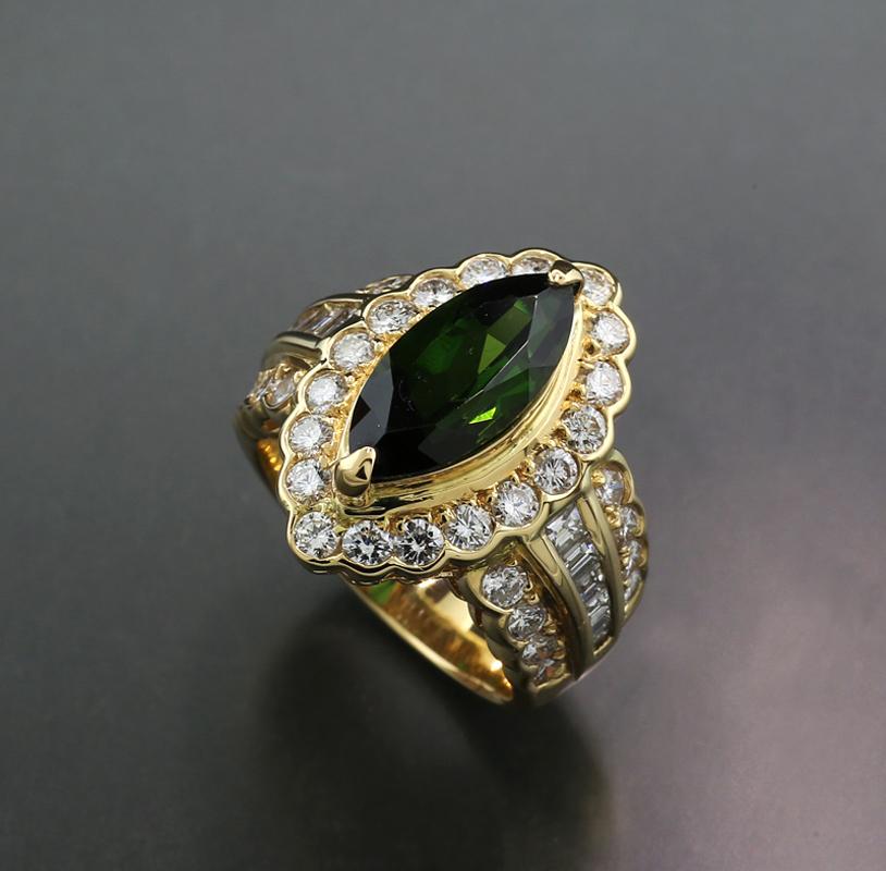 an exquisite ring, featuring a deep, eye-clean moss green tourmaline, weighing approximately 2.76 carats, faceted in a navette shape and set in an open, delicate setting. The boat-shaped bezel is held by two prongs and rests atop a two-pointed ring