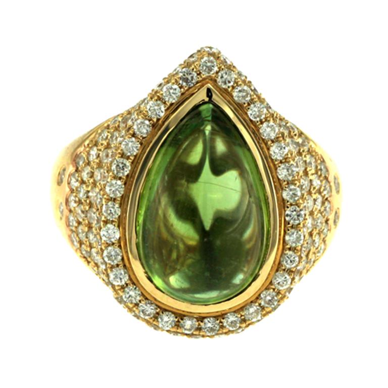 This stunning tourmaline ring is an exquisite piece of jewelry that is sure to turn heads. Featuring a large 7 ct. cabochon tourmaline with a delicate and shifting coloration, this ring is a true marvel of gemstone craft. When viewed head-on, the