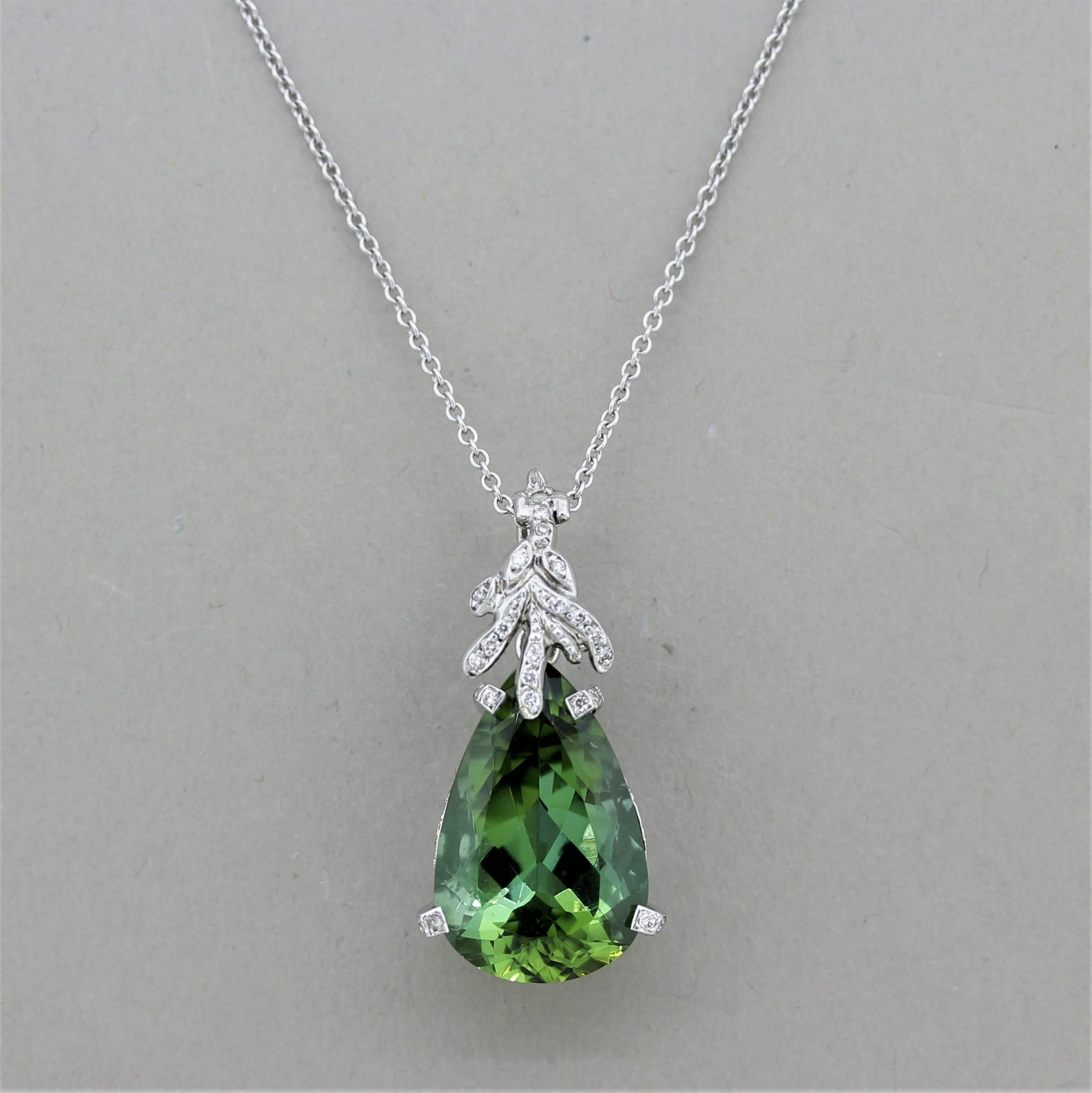 A fine gem tourmaline weighing 14.05 carats is the centerpiece of this floral style pendant. The tourmaline has a bright and vibrant green color with a soft blue undertone. It is set under a floral pattern set with diamonds suggesting the tourmaline