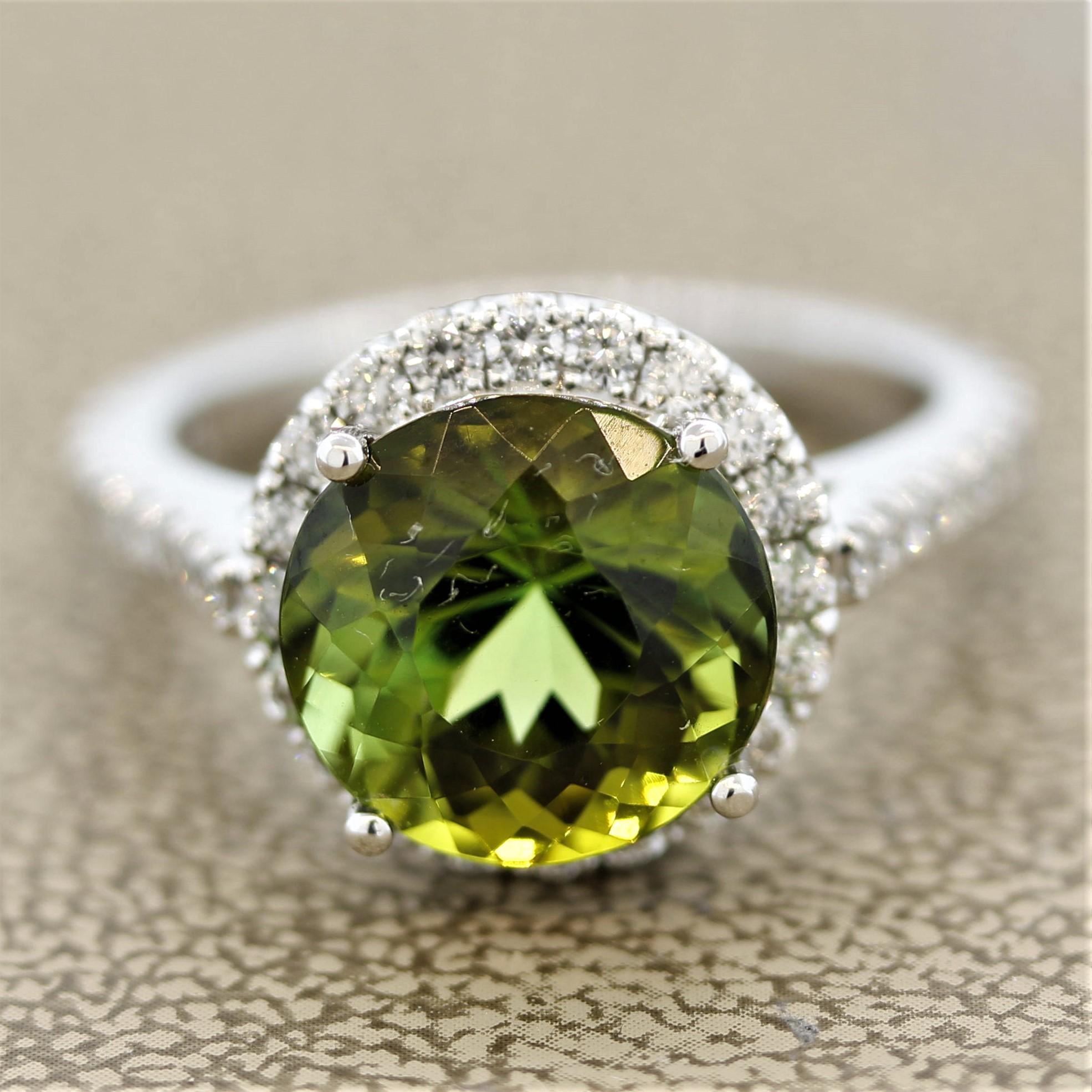 A lovely tourmaline ring. It features a 5.36 carat round cut tourmaline with a lush green color and great brilliance. It is accented by 0.73 carats of round brilliant cut diamonds which halo the tourmaline and are set on the sides of the ring.