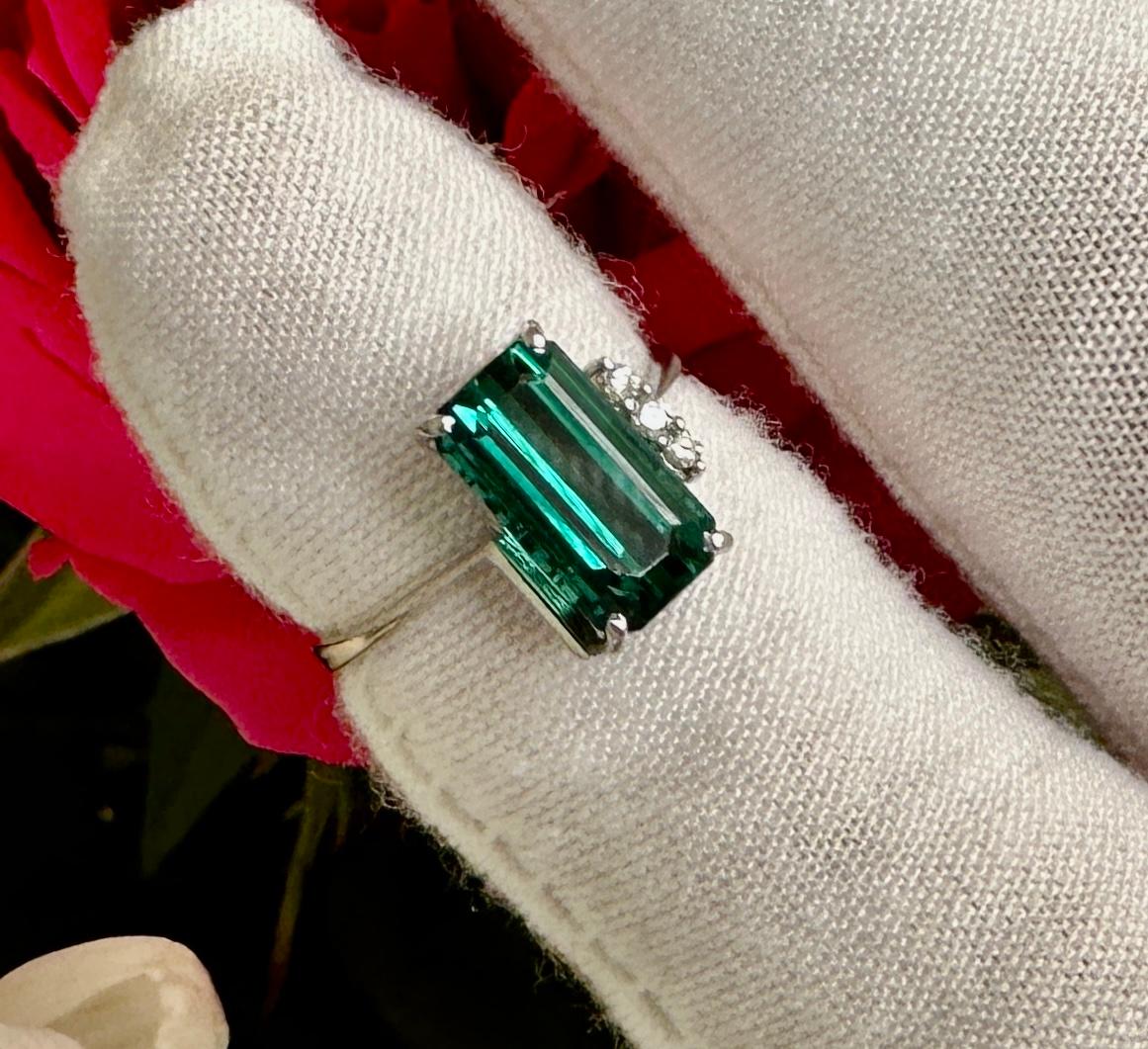 This is a magnificent Emerald Cut Green Tourmaline Ring with three sparkling white Diamonds in 18 Karat White Gold.  The extremely Fine Green Tourmaline is emerald cut and is 11mm by 6mm by 5mm deep and is approximately 2.6 Carats. 
It is a gorgeous