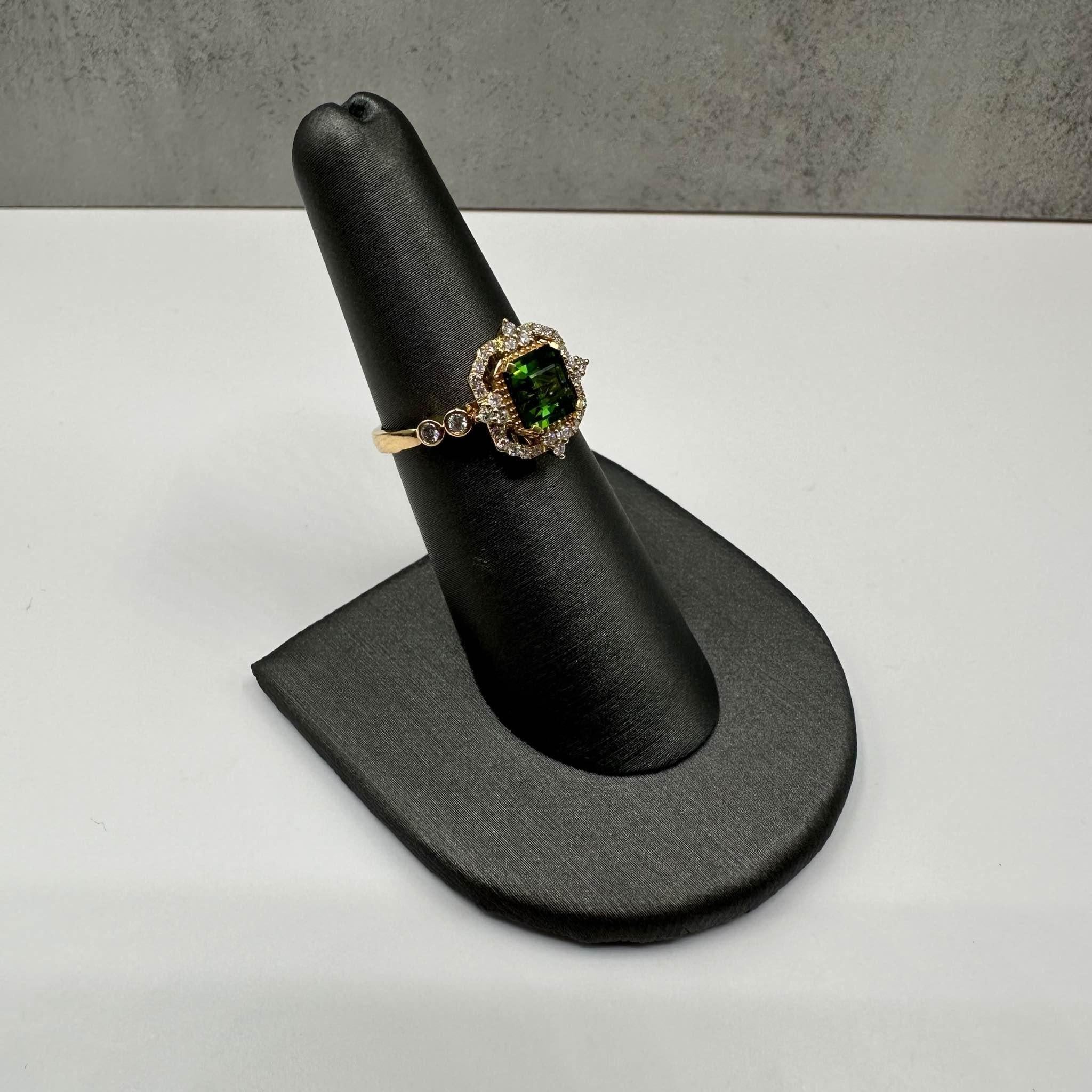 This stunning Green Tourmaline and Diamond Ring in 18kt yellow gold features a 1.26ct emerald-cut green tourmaline, complemented by 0.30ct of natural FG VS/SI round diamonds. The vibrant green tourmaline is beautifully accented by sparkling