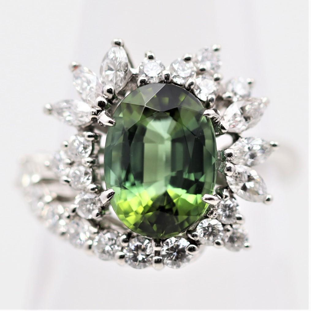 An elegant ring featuring a 3.90 carat oval-shape tourmaline with a vibrant green color and a hint of blue. It is complemented by 1.25 carats of round brilliant and marquise-shape diamonds set around the tourmaline in a sunburst design.