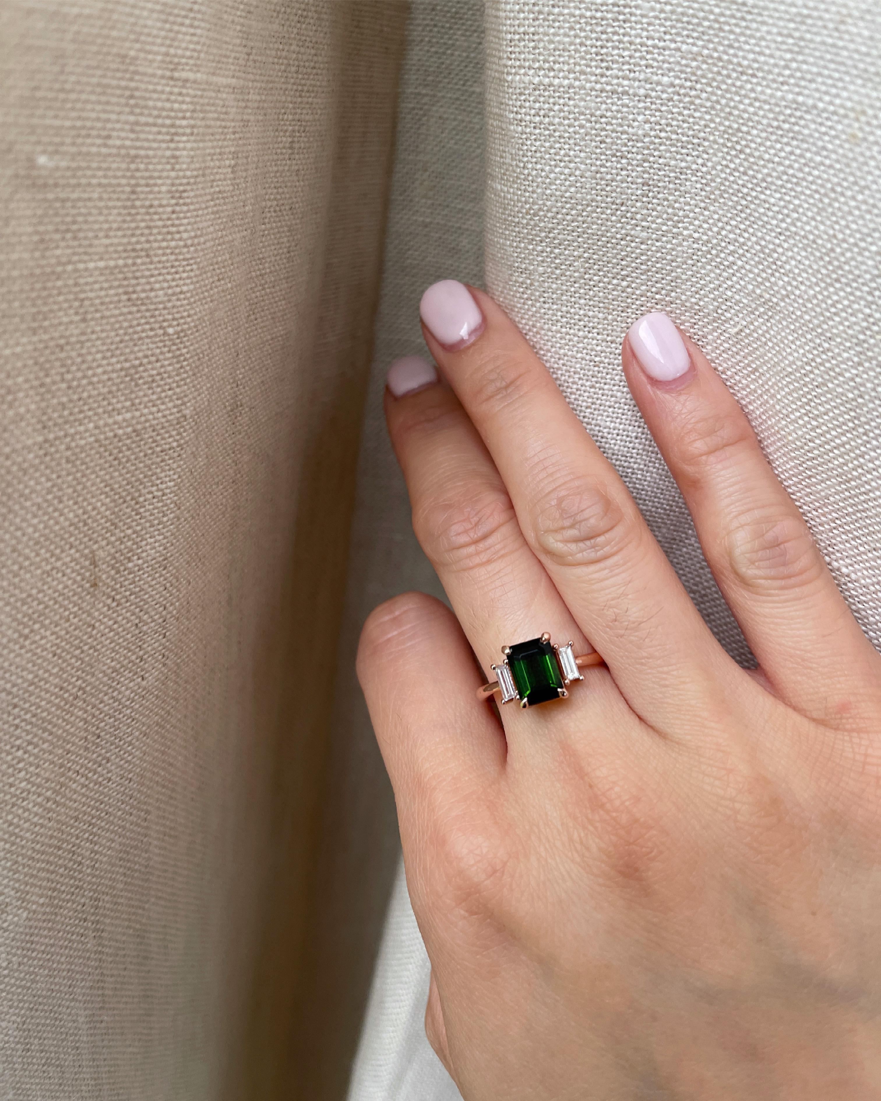 Emerald cut green tourmaline adorned with baguette diamonds
Three stone ring
Green Tourmaline Size: 8 x6 mm
Baguette Diamonds: Two 4.5 x 2 mm
Diamond Clarity: SI
Diamond Color: GHI
Diamond weight: 0.12 carat each
Total Diamond Weight: 0.25