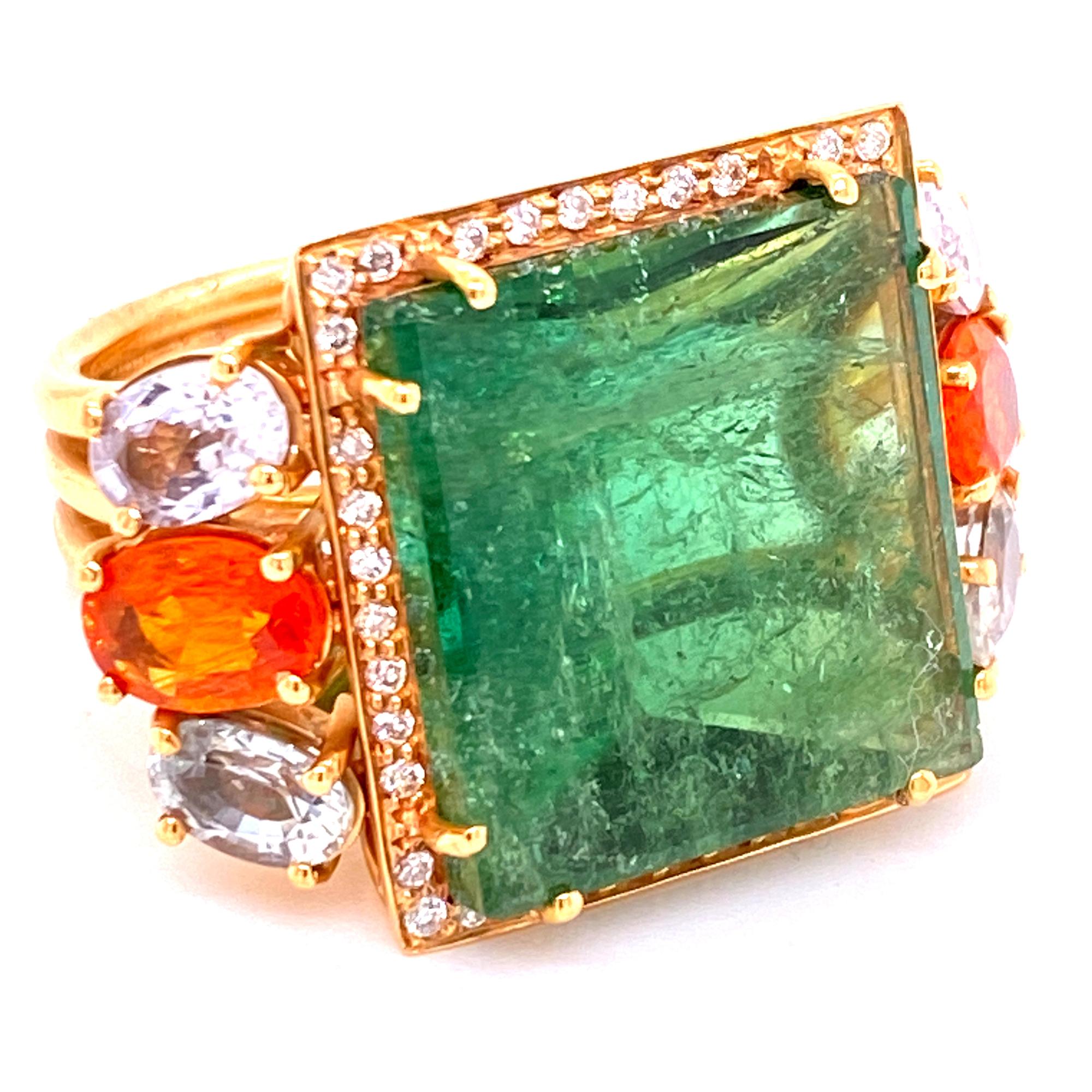 Fabulous square green tourmaline, fire opal, sapphire, and diamond ring fashioned in 18 karat yellow gold. The square cut 22 carat green tourmaline gemstone is surrounded by 38 round brilliant cut diamonds( .38 ctw). The mounting also features two
