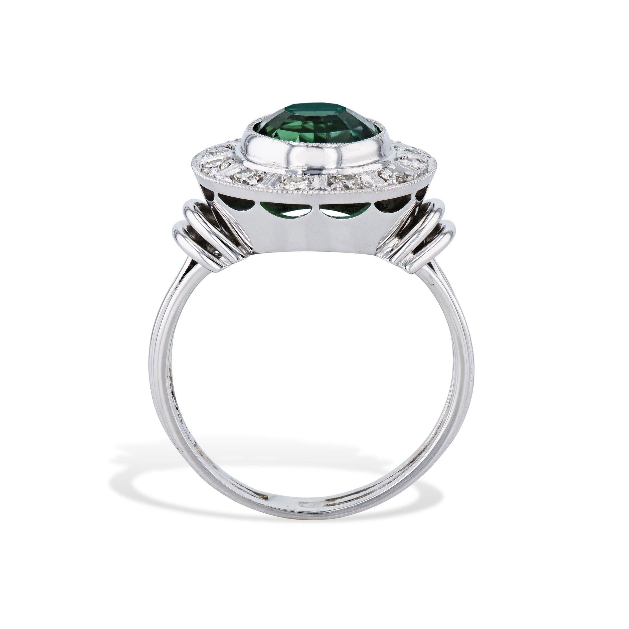 Enchant your look with this gorgeous 18kt. white gold Green Tourmaline Milgraine Diamond Estate Ring! Boasting an 8mm center Green Tourmaline framed by 12 round cut diamonds in a Milgraine setting. this luxurious size 7.25 ring will make every