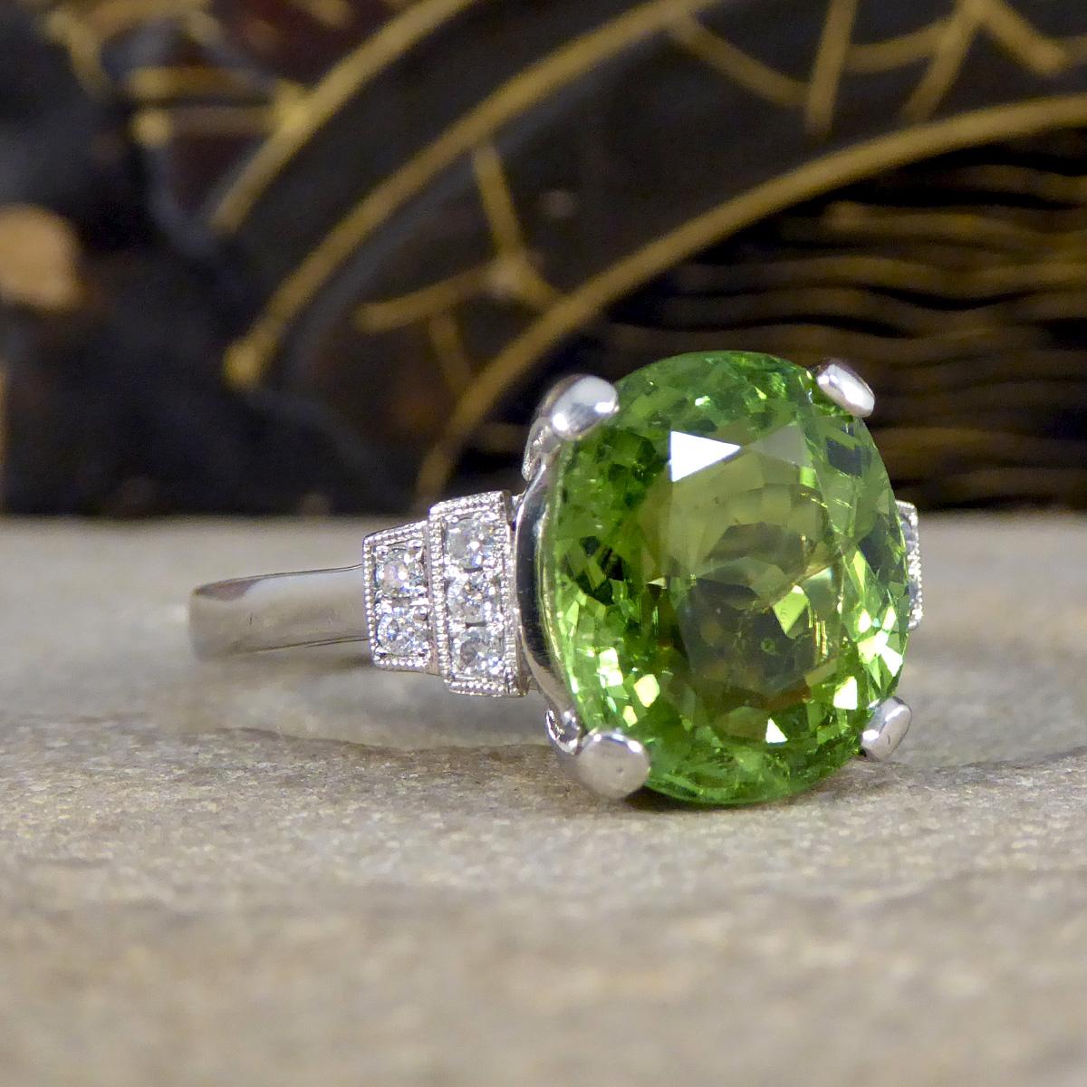 This Green Tourmaline Ring, set in platinum with an art deco-inspired design, offers a stunning blend of vintage charm and contemporary elegance. At the centre of this exquisite piece sits a vivid green tourmaline, securely held by a classic