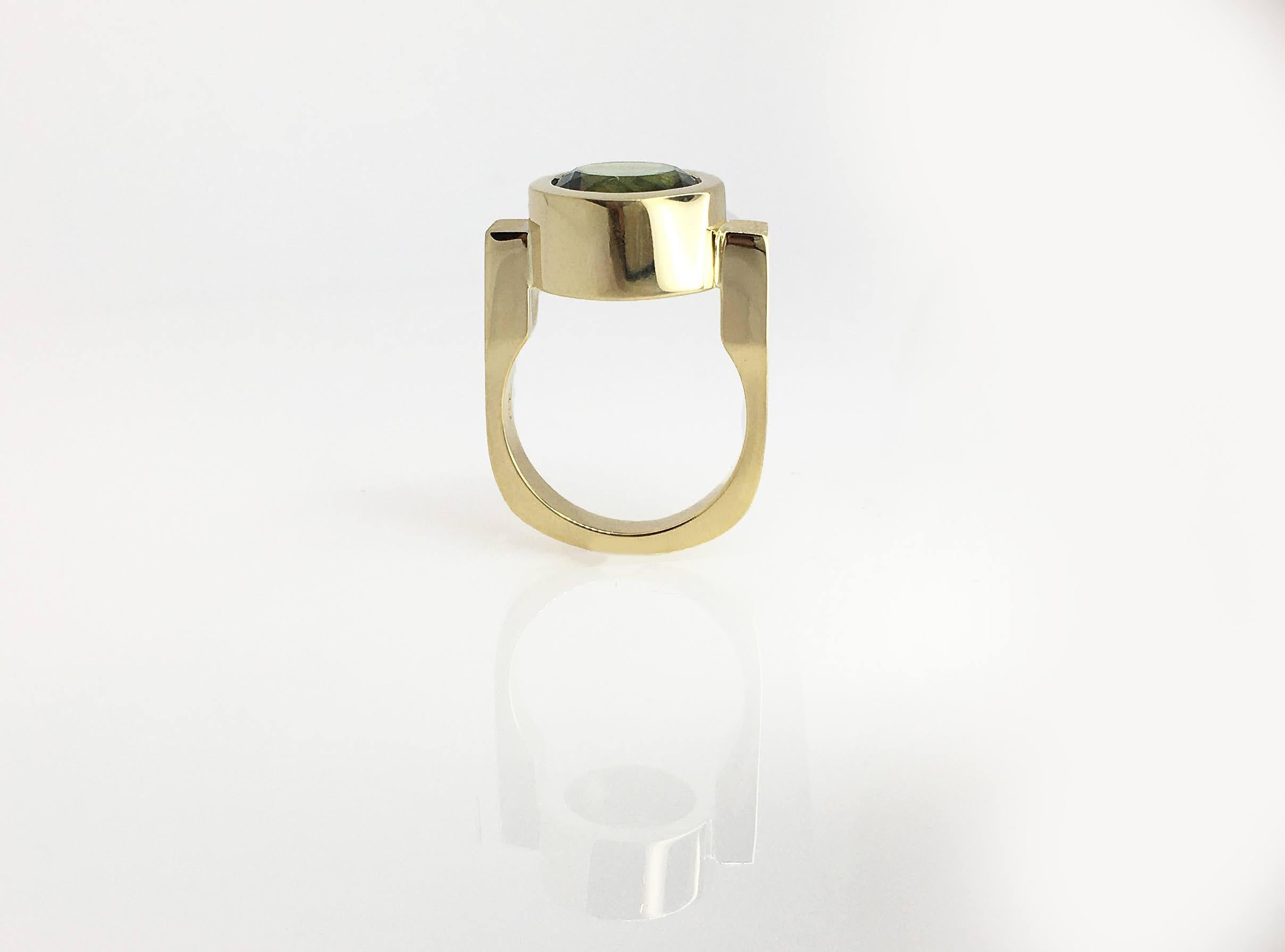 This Green Tourmaline Bezel Ring is shown here in yellow gold. A round bezel set on a squared band with a high polish finish creates an infinitely modern look. Be careful, this ring will bring you much attention, if that’s what you’re aiming for,