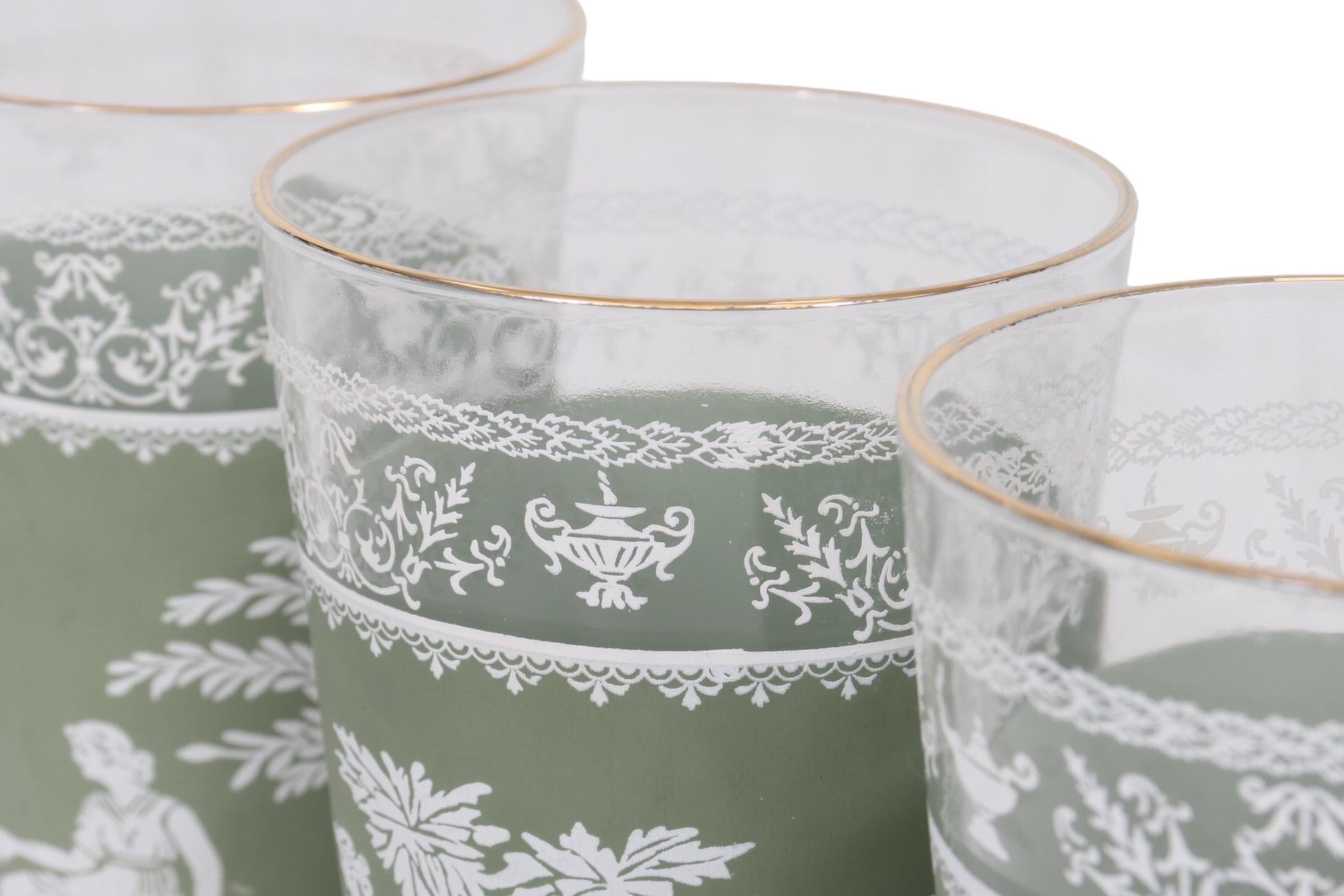A set of six olive green and white transferware glasses with gold rims. Men and women in Greco-Roman clothing converse beside a plinth and an olive tree. Dimensions per glass.
 