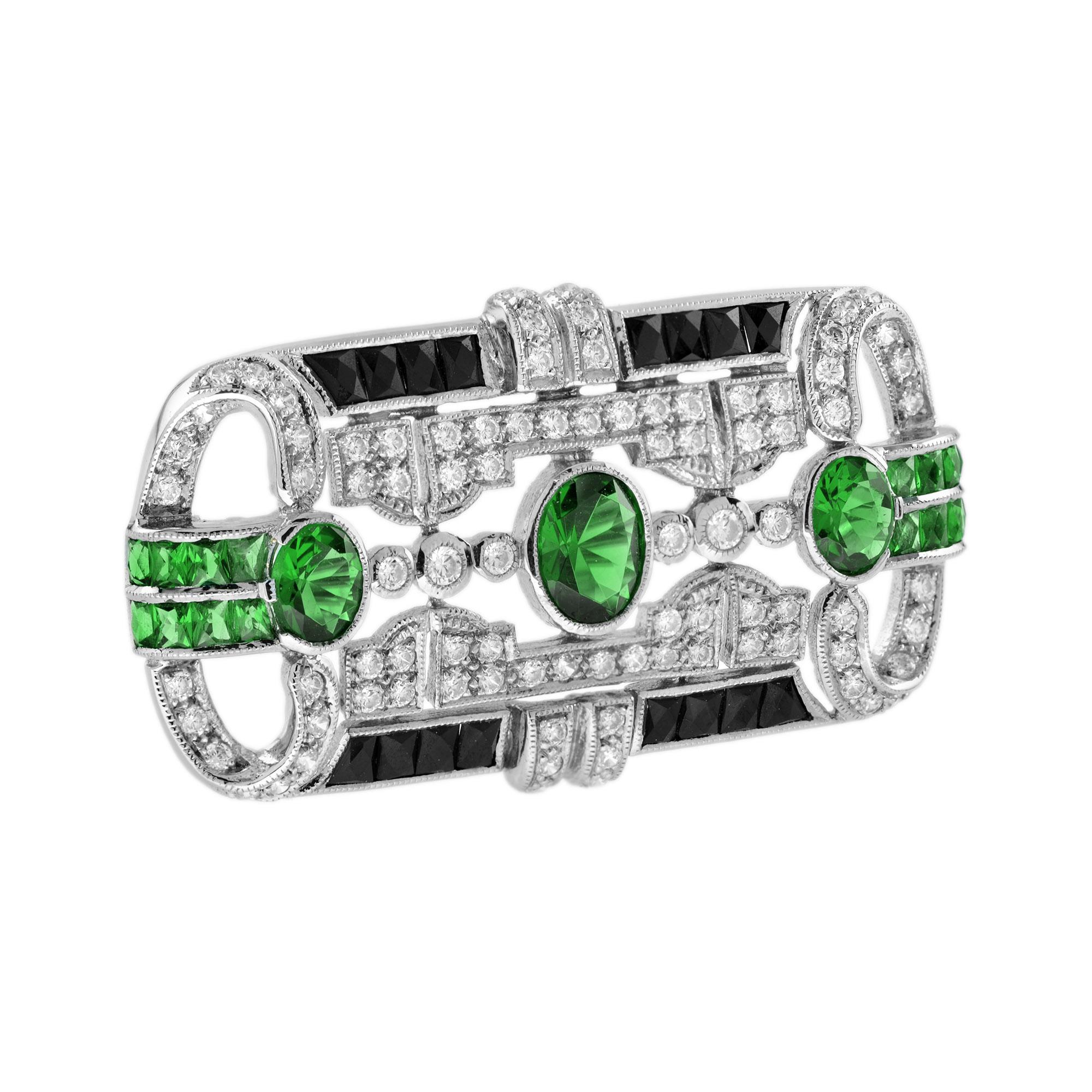 Diese goldene Brosche ist ein exquisites Beispiel für Art-Déco-Schmuck und enthält Tsavoriten, Onyx und Diamanten in einer schönen geometrischen Form. Ein zentraler sehr feiner ovaler Tsavorit und zwei weitere Tsavorite auf der linken und rechten