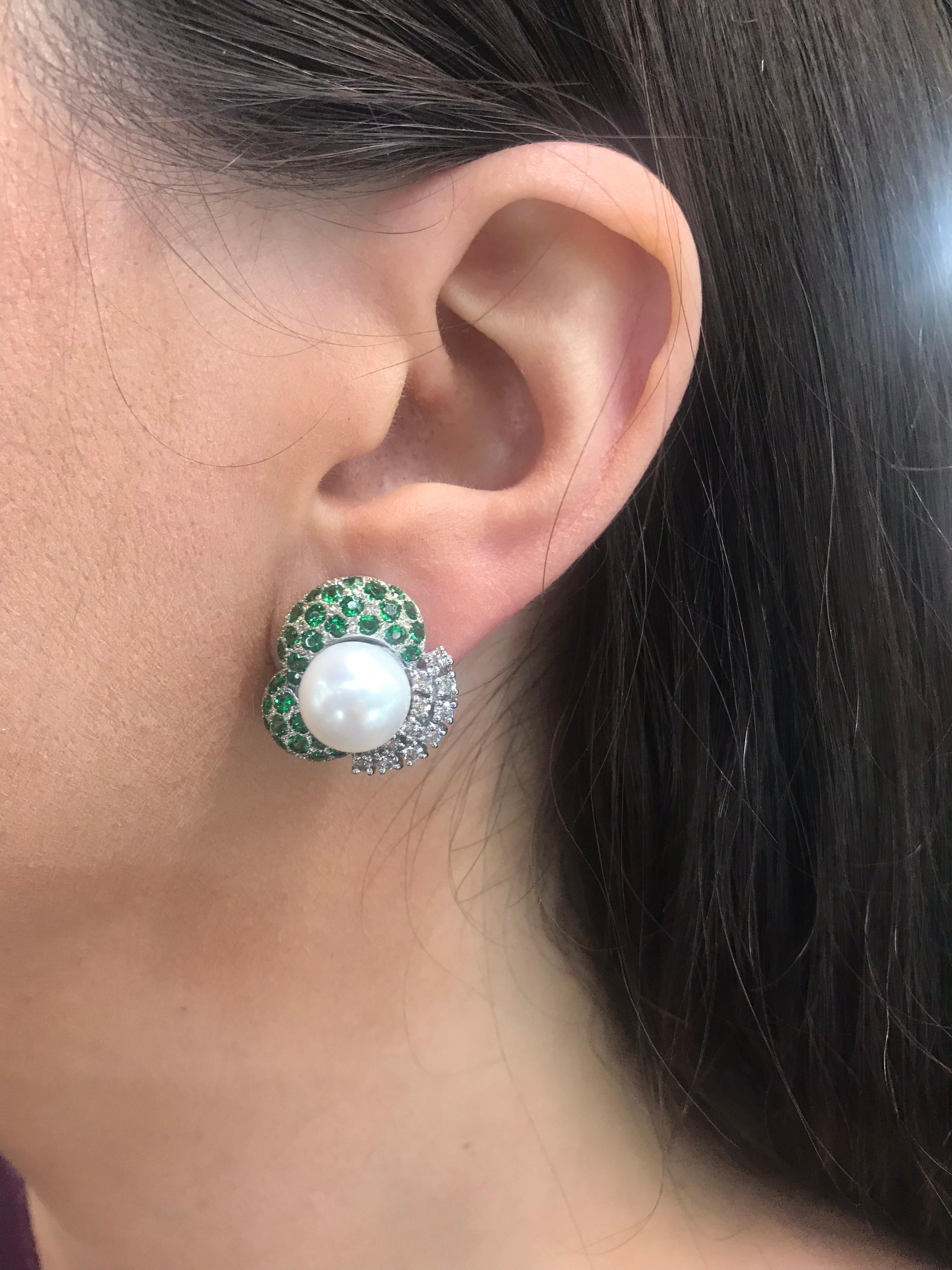 18K White gold stud earrings featuring two white pearls measuring 10-11 MM, flanked with vivid green Tsavorite gemstones weighing 2 carats and round brilliants weighing 0.72 carats.
Color G
Clarity VS-SI

Very comfortable on the ear!!!
