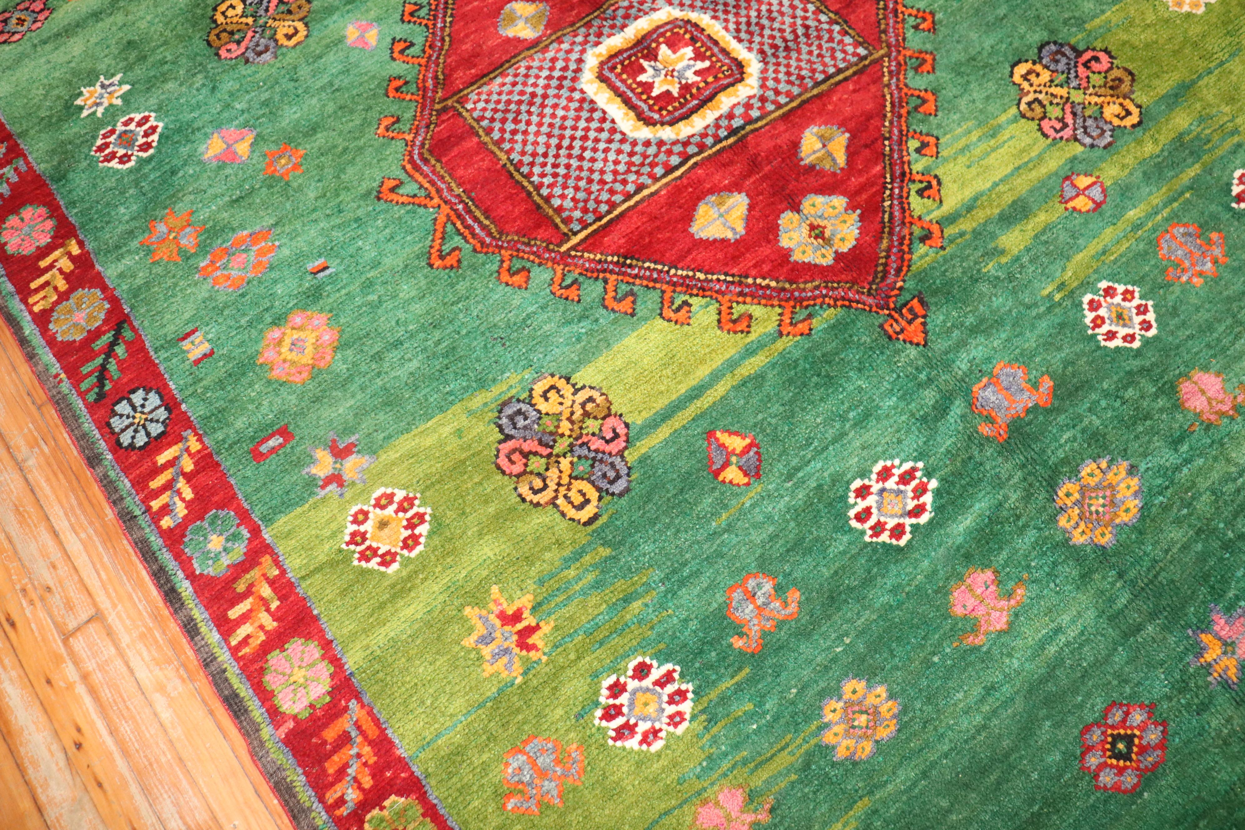 Bohemian mid 20th Century Turkish Rug with a floral design on a striated green field.

6'11'' x 12'9''