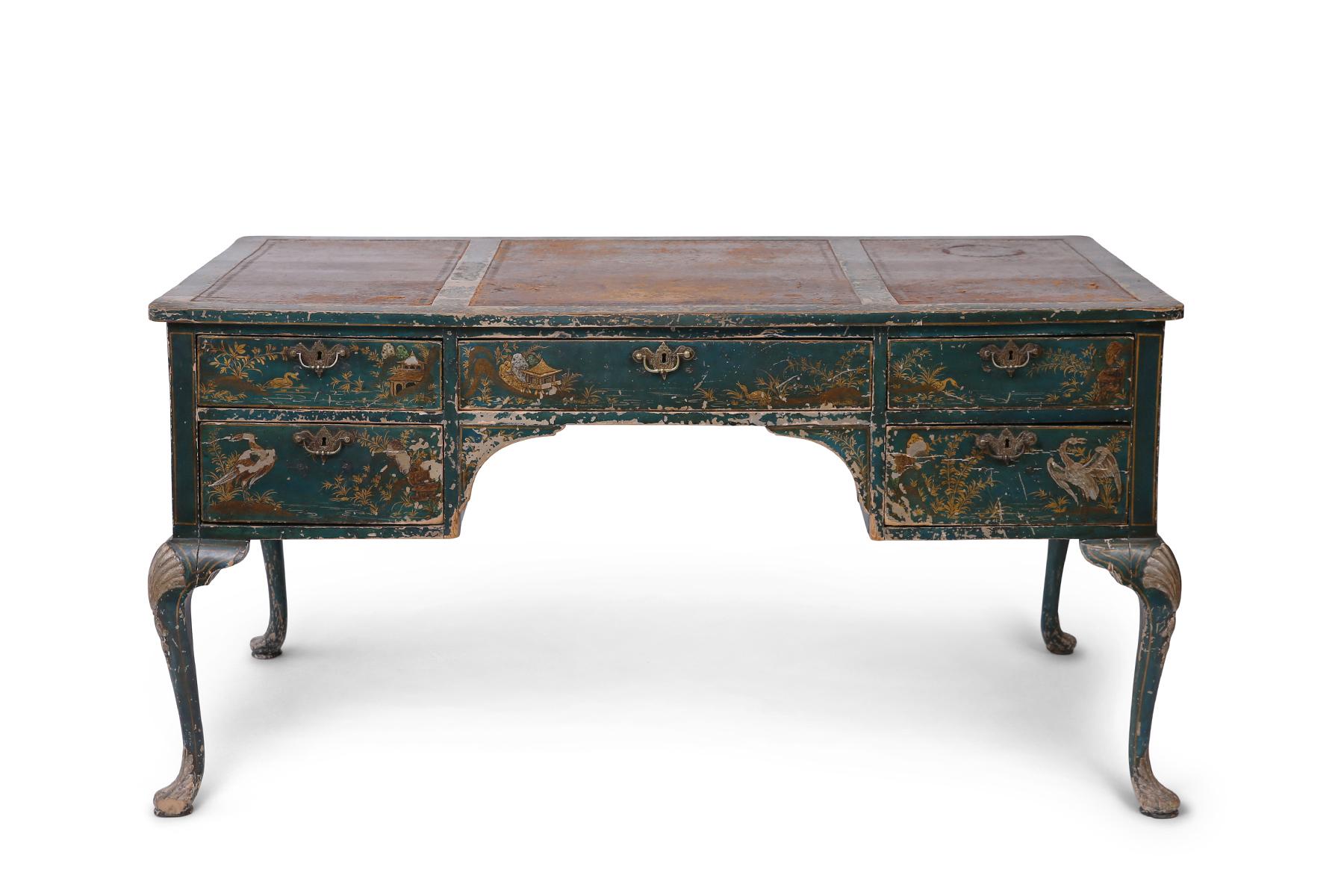 An early 20th century inverted breakfront green/blue-tinted writing desk in the Queen Anne style with painted gold/ochre pagodas, foliage and bird motifs. The desktop has a worn, patina-ed brown leather that gives the piece even more rich