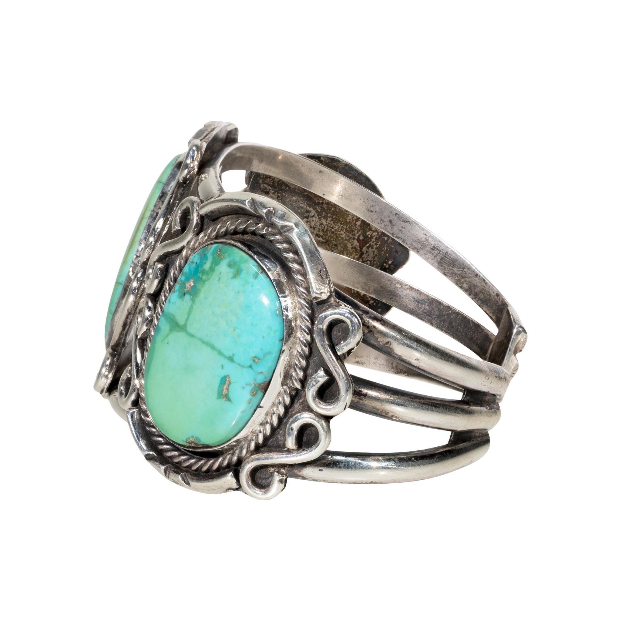 Bracciale in turchese verde e argento sterling. Pietra di Eash incastonata in un castone liscio con bordo in corda ritorta e dettagli a volute. Le pietre sono di un bel verde chiaro con matrice blu e oro sottile. Incastonato in un bracciale a tre