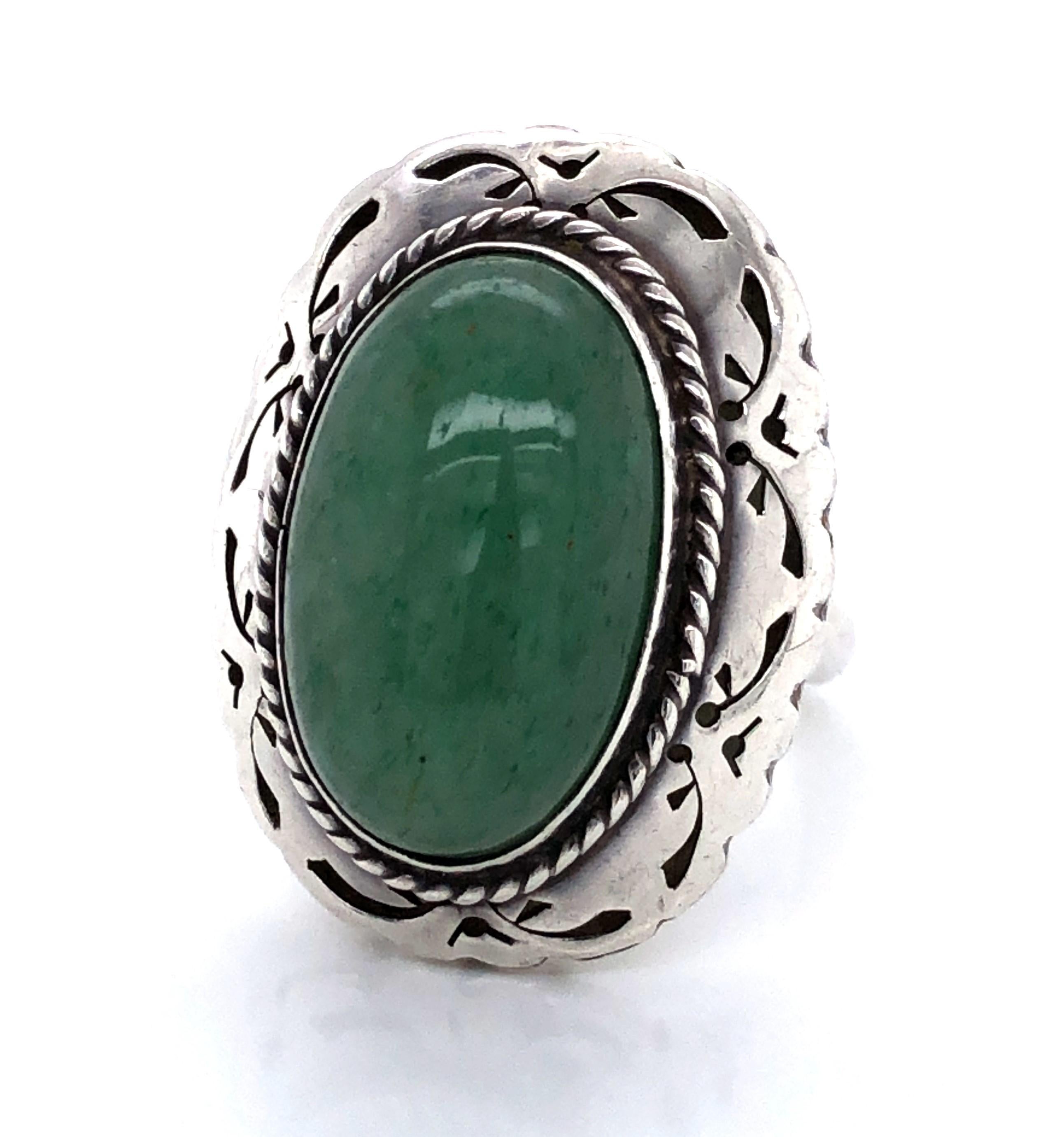 A large polished green turquoise cabochon is the focal point of this Southwest style statement ring. The over five carat oval stone, measuring 12 x 20mm, sits proudly on the reticulated raised sterling silver ring head which is decorated with silver