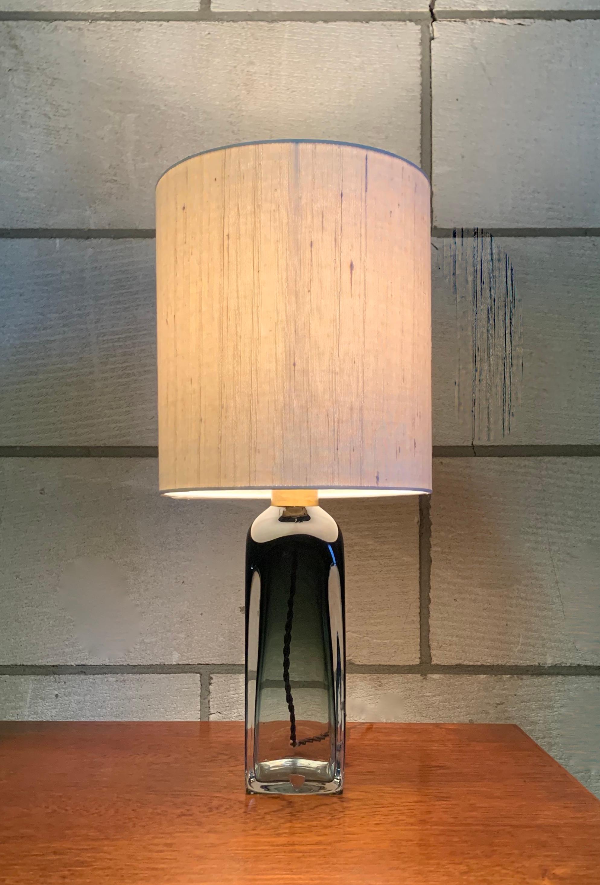 Beautiful green 'underfång' glass table lamp by Swedish designer Carl Fagerlund blown at Orrefors Sweden, circa 1970. 
The lamp comes with a new custom handmade shade upholstered in a raw silk fabric and is equipped with new electricity and