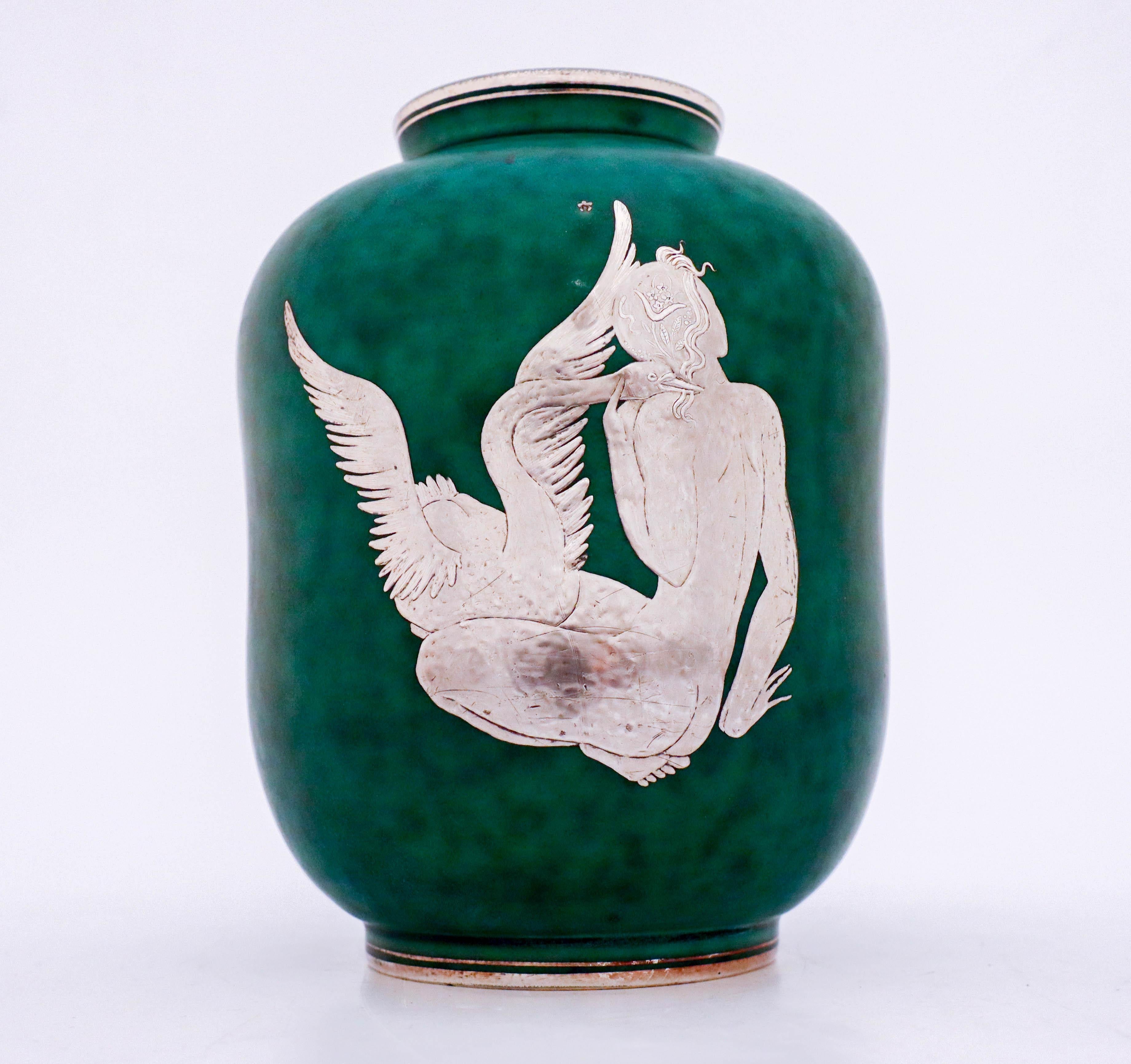A vase in stoneware of model Argenta designed by Wilhelm Kåge at Gustavsberg with silver decor of a girl with a swan, this vase is 19 cm high and 13.5 cm in diameter. It´s in mint condition and marked as on photo.