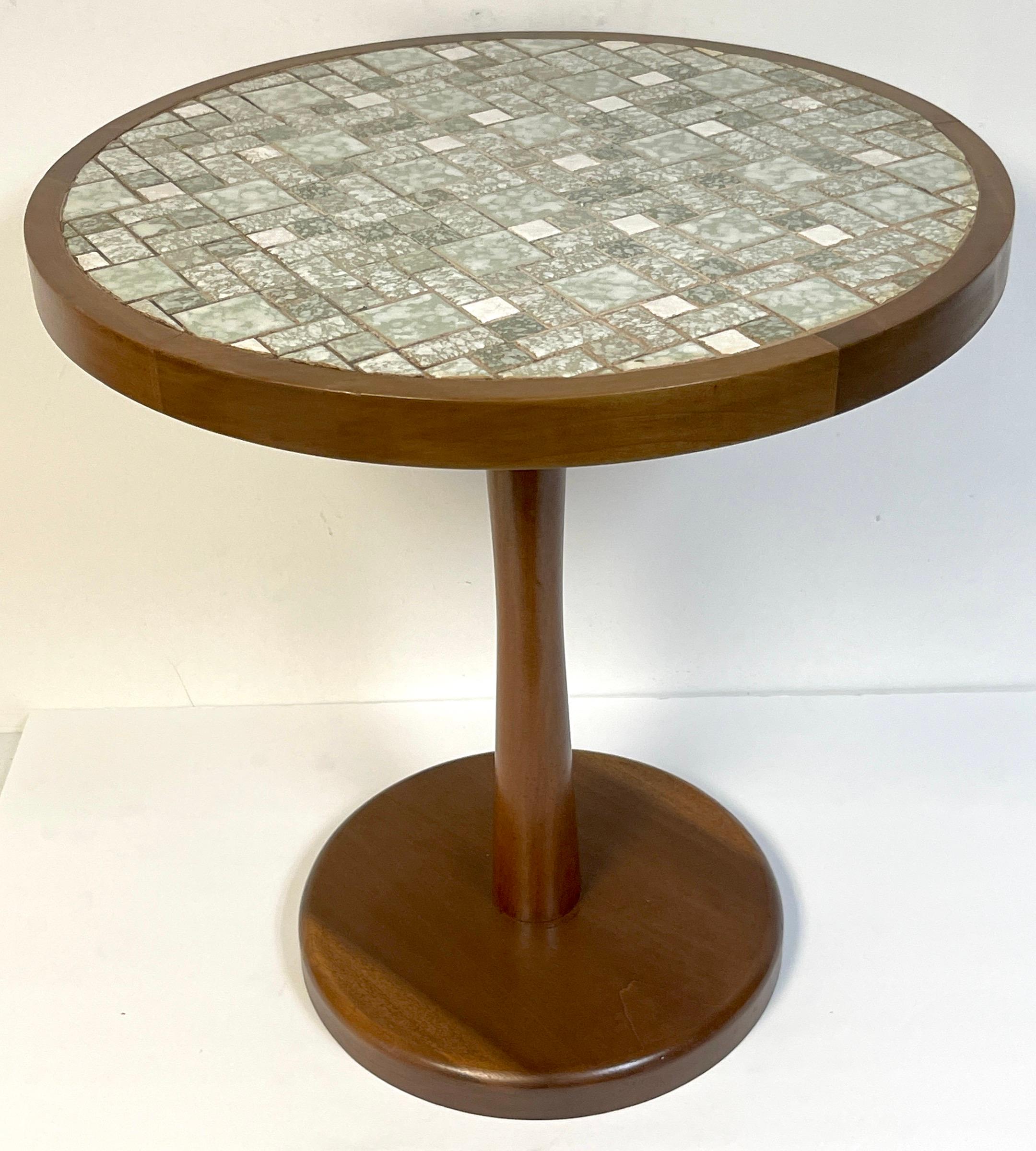 Mid-century green & white tile top drinks table, style of Gordon & Jane Martz
USA, circa 1960s 

Of circular form with inset square and rectangular mosaic green and white porcelain tiles, raised on a mahogany column with 12-inch round