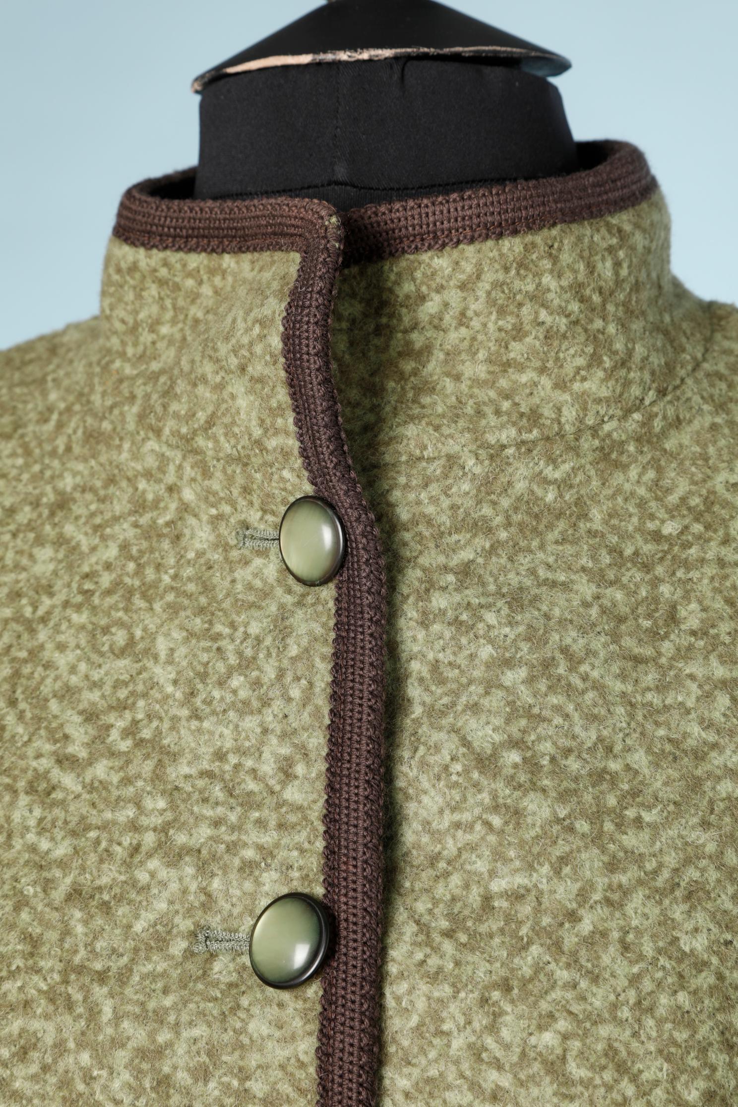 Jupette en laine verte avec passepoil en tresses brunes. Composition du tissu principal : 42% laine, 51% alpaga, 7% polyamide. Doublure en acétate. 
Des pads d'épaule. Boutons et boutonnières au milieu du devant. Fente au milieu du dos = 8cm
+Poches