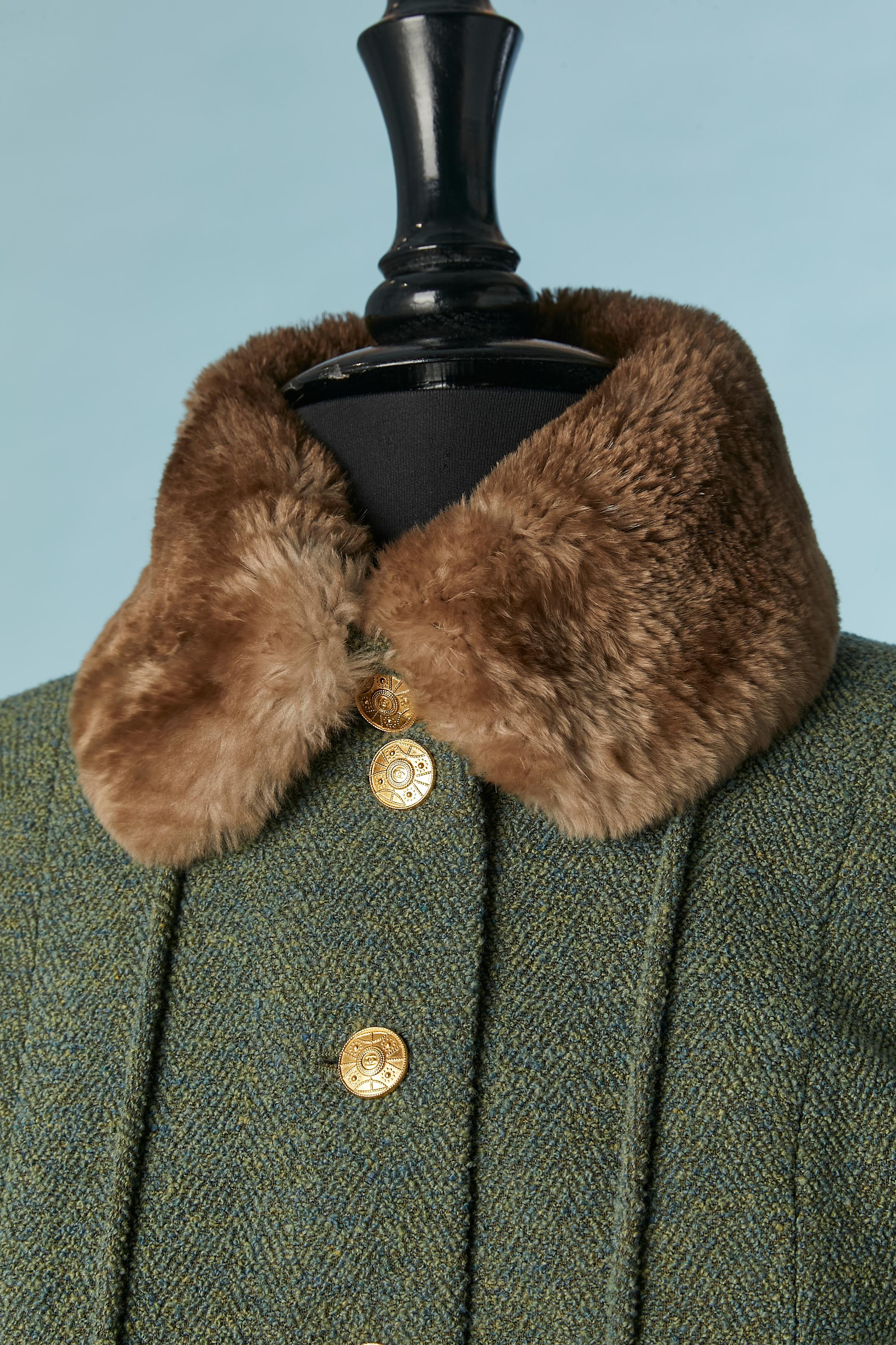 Green wool tweed skirt suit with gold metal branded buttons and fur ( probably chinchilla) pompoms . Main fabric composition: 85% wool, 15% cashmere. Silk branded lining. 
Shoulder-pad. Pockets on both side. 
SIZE L (jacket) and M ( skirt) 
