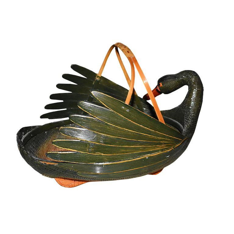 Painted in dark green, this woven basket is created from wood, rattan, and bamboo. Strips of wood are arranged in the shape of a duck or swan. The sides have splayed pieces of wood that are affixed together to resemble feathers. Protruding from the