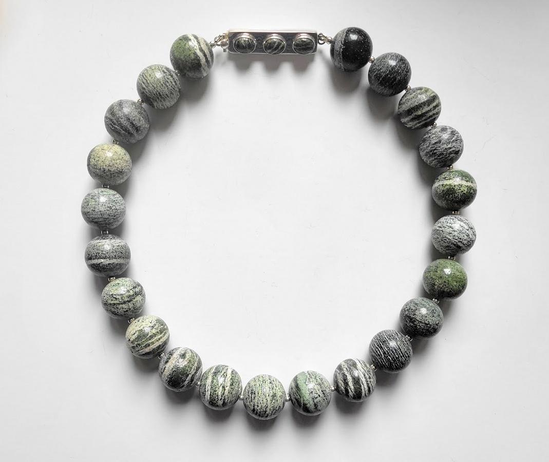 The necklace measures 20.5 inches (52 cm) in length and is adorned with smooth round beads 20 mm in size. Crafted from Chrysotile serpentine, also known as Green Zebra Jasper, primarily sourced from Canada and the USA, this necklace showcases the