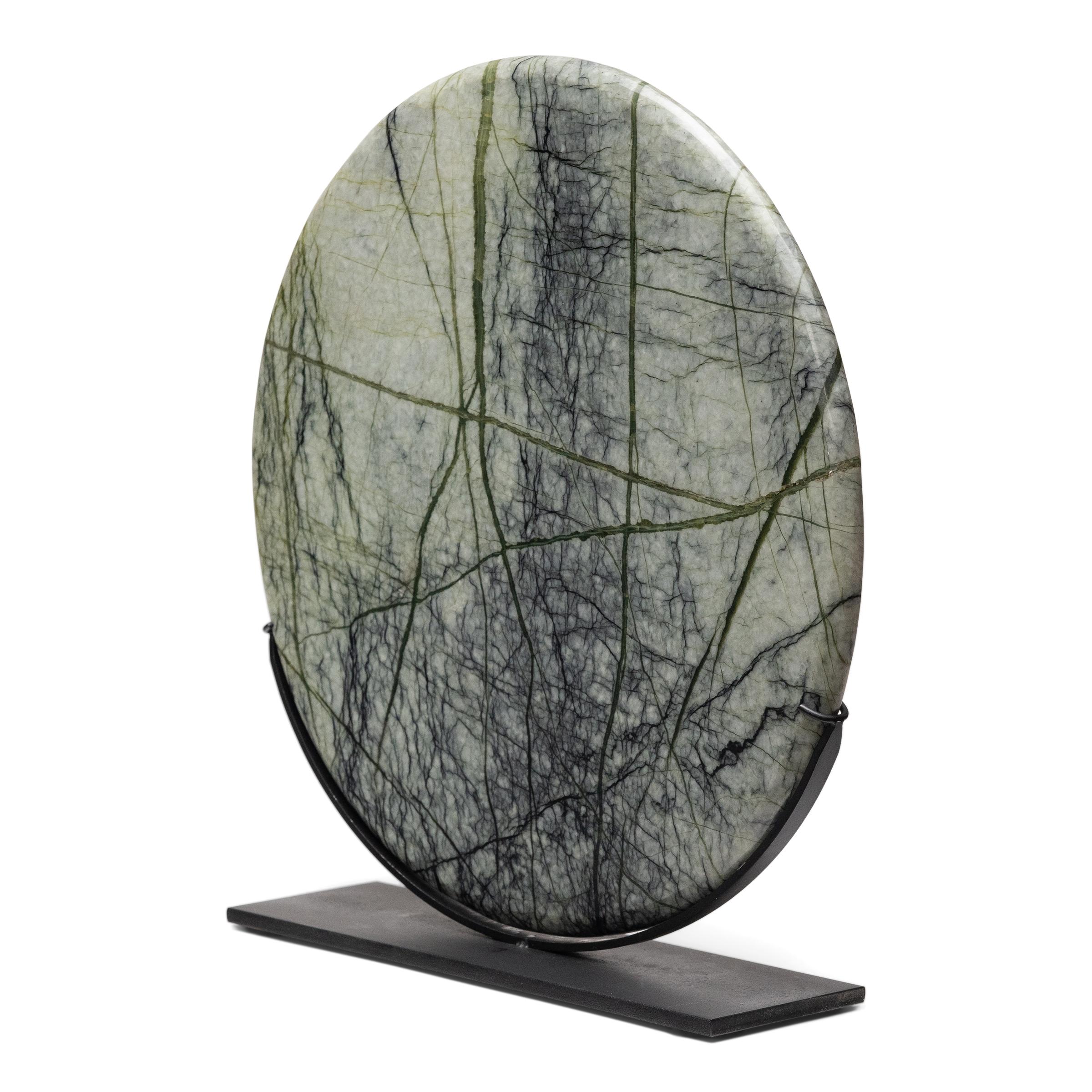 A well-chosen stone is a resting place for the mind, inspiring calm and contemplation. Marked by currents of jadeite, moss agate, and serpentine, this greenery stone disc evokes the grandeur of nature with beautifully irregular patterns that capture