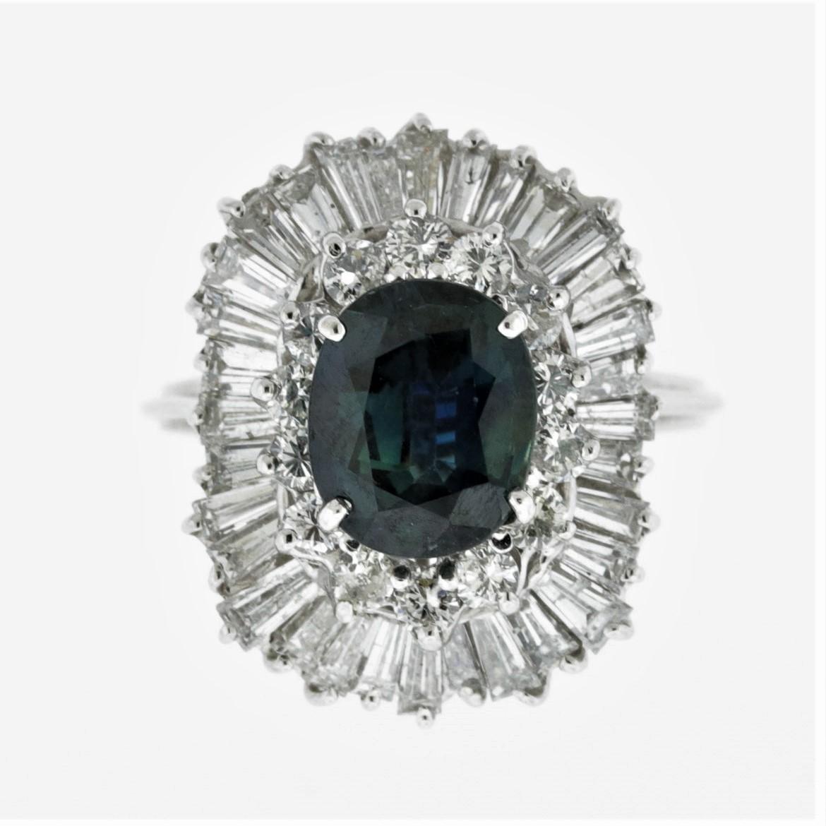 A lovely ring featuring a uniquely colored natural sapphire. The sapphire weighs 2 carats and has a greenish-blue color that sparkles in the light. It is complemented by approximately 3 carats of round brilliant and baguette-cut diamonds set around