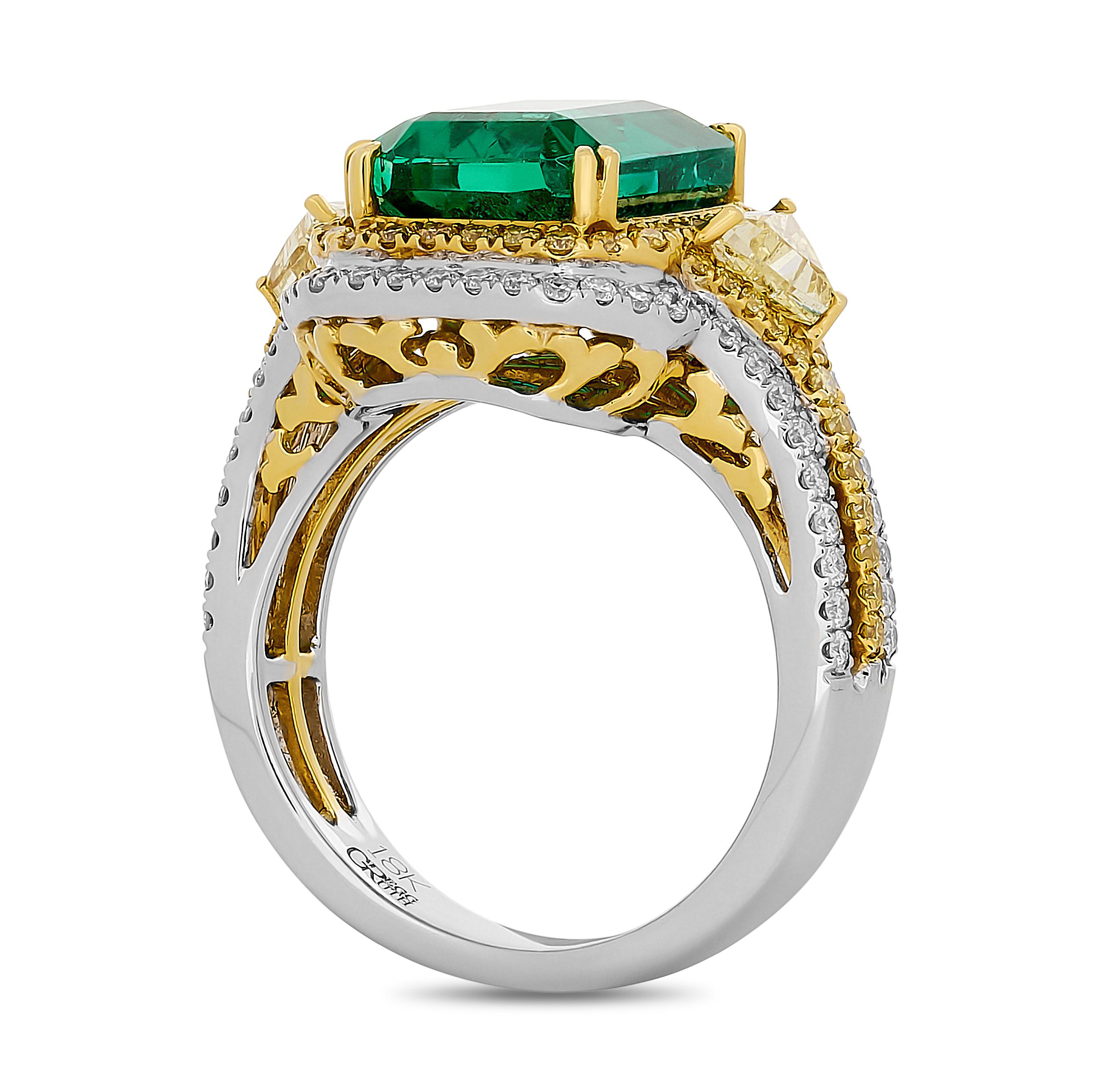 This exquisite Gregg Ruth ring showcases a prominent emerald-cut emerald, flanked by two trillion-cut yellow diamonds and encircled by a double halo of white and yellow diamonds, set on a diamond-encrusted split shank.

The center emerald weighs