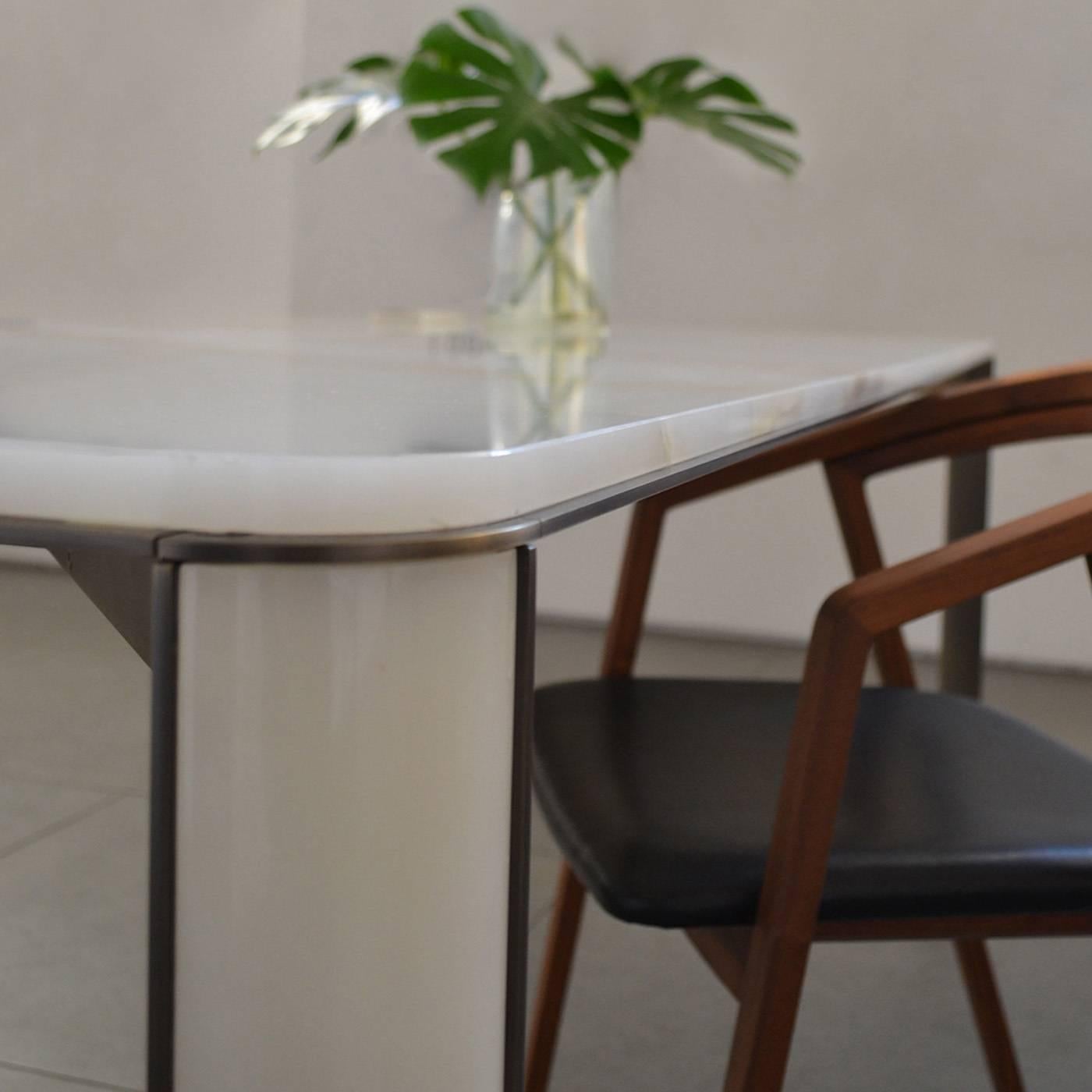 This dining table, designed by Monica Geronimi, features a timeless design that combines modern lines, curved angles, and Classic materials. The structure in steel supports a top and mounted legs in onyx. A splendid table that can be used in the