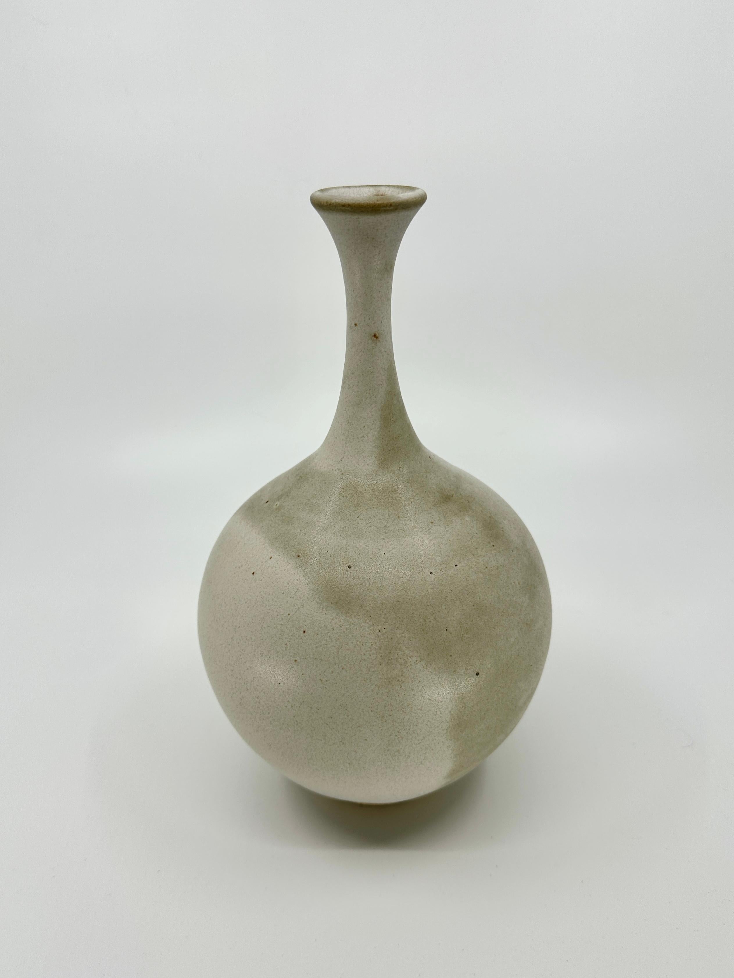 Wheel-thrown and hand-turned bottleneck vessel in beautiful gray/beige and cream colors with small spot of terra cotta color in the mouth. Handmade from light stoneware, this piece serves as a testament to the timeless beauty of heirloom pottery,