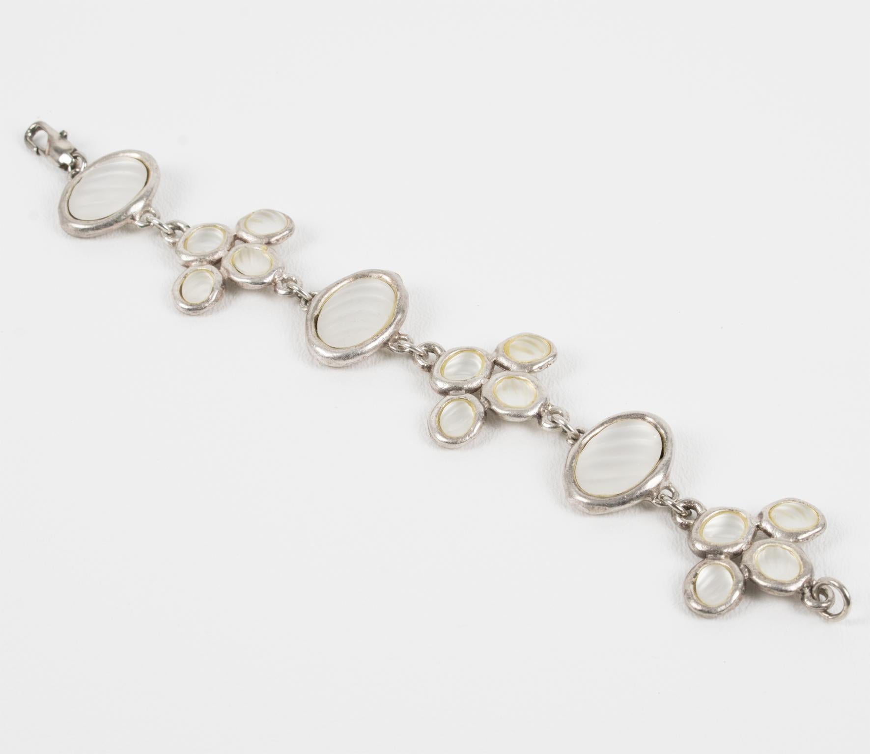 Madame Gres Paris diseñó esta hermosa pulsera de eslabones en la década de 1980. La pieza presenta un diseño geométrico modernista con marcos de elementos metálicos plateados rematados con cabujones de vidrio esmerilado opalescente con motivos