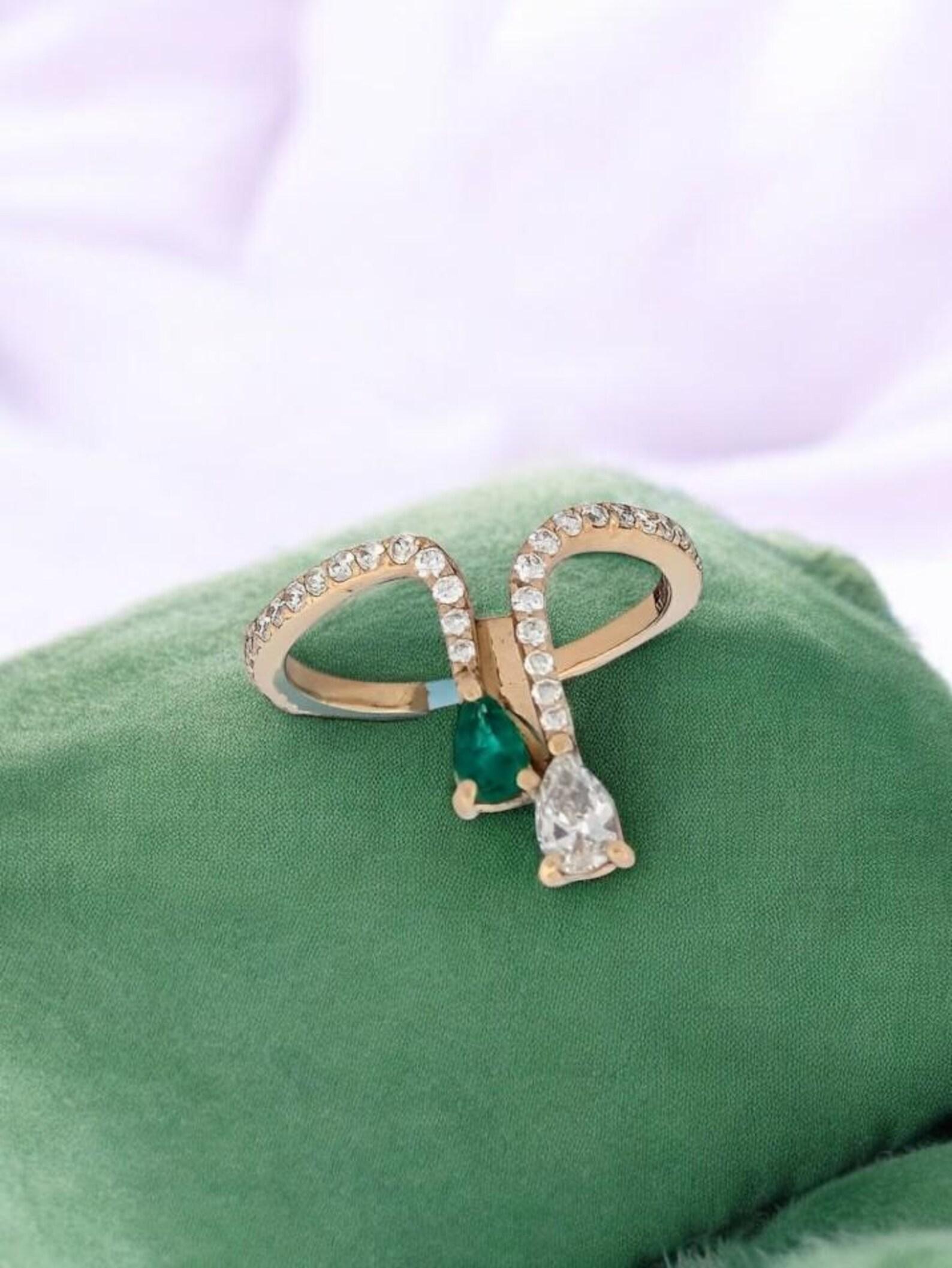 Enhance your style with the Greta Emerald Ring, an exquisite piece that combines timeless beauty with modern design. Crafted from luxurious 14k yellow gold, this ring showcases a striking teardrop-shaped 1/4 ct diamond, surrounded by a stunning pave