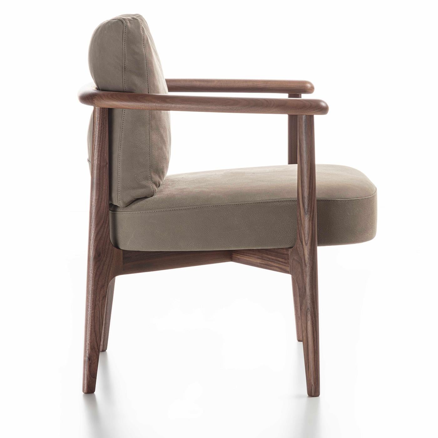 This stunning armchair in solid Canaletto walnut exemplifies modern sophistication with its harmonious curves and timeless neutral tones. The 45cm-high seat and backrest - embraced by a fully-enveloping back that flows into the armrests (H 63cm) -