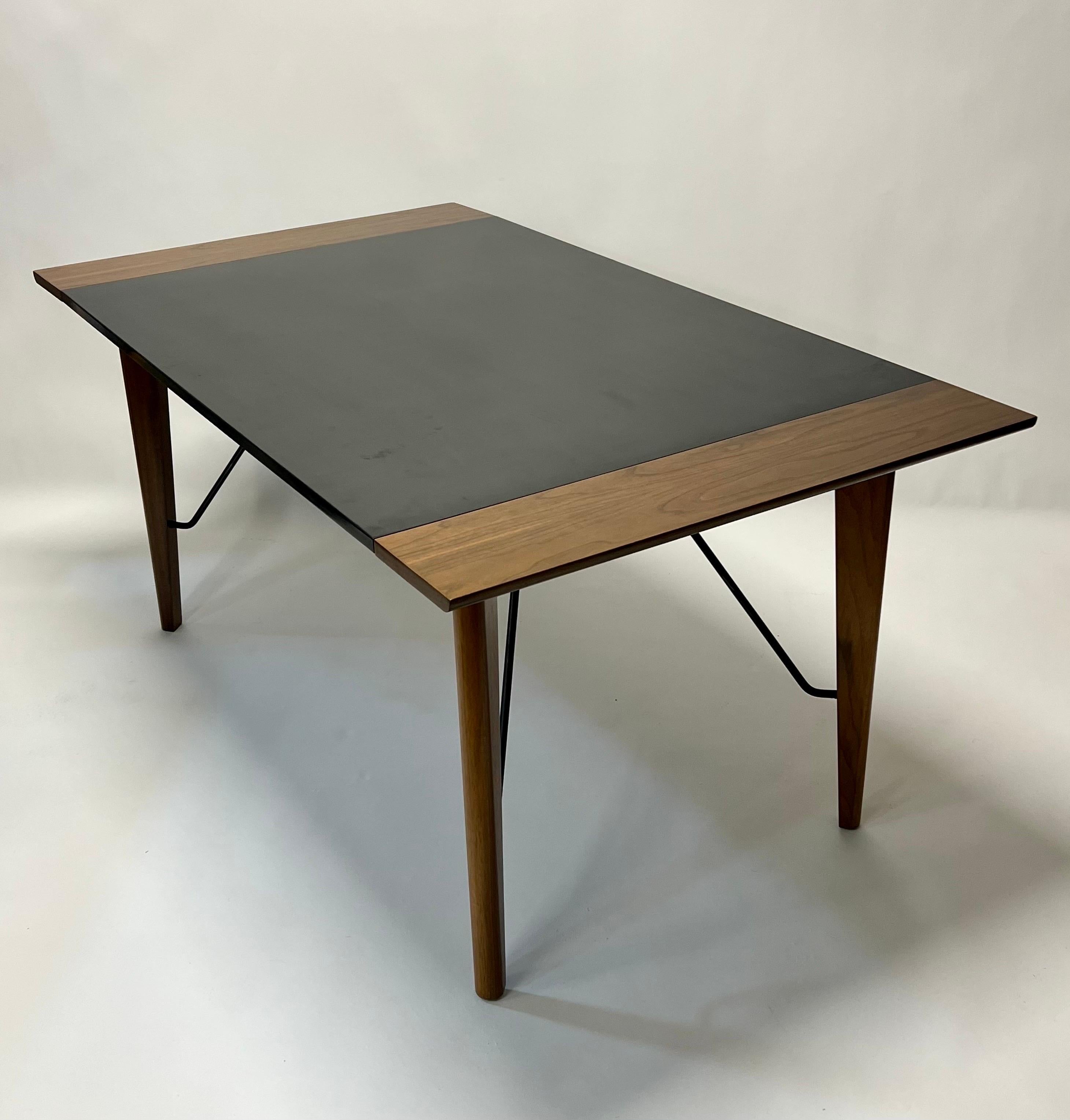 Rare and iconic expanding walnut & black laminate dining table with iron cross-stretchers by famous Swedish/California designer/architect, Greta Grossman for Glenn of California c1952. This table was also offered without the iron cross-stretcher,