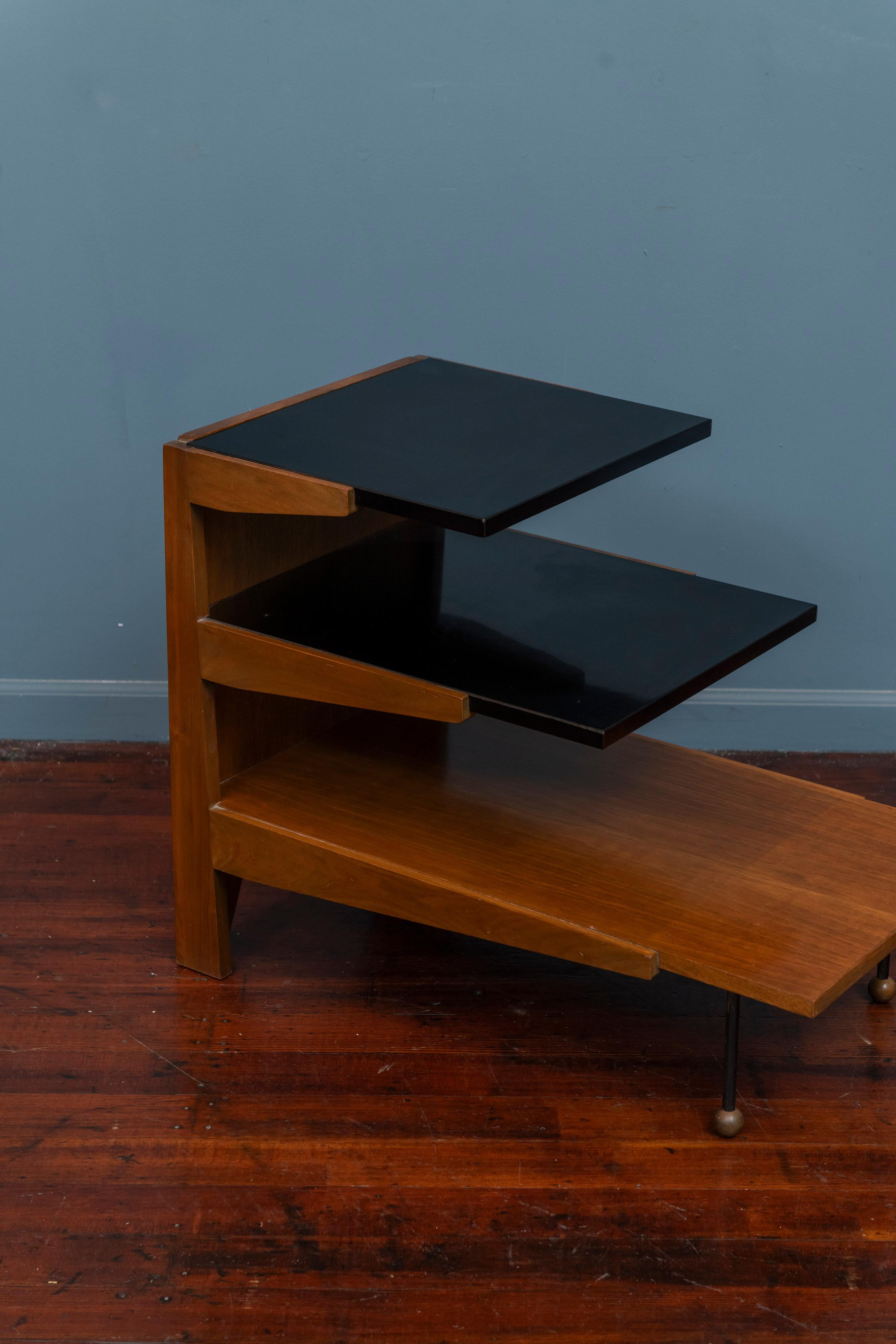Greta Magnussen Grossman tiered side table for Glenn of California. 
A rare form by an iconic designer seldom seen on the market, a tiered table for books, objects or magazines. Made from bleached walnut, black laminate and steel legs capped off