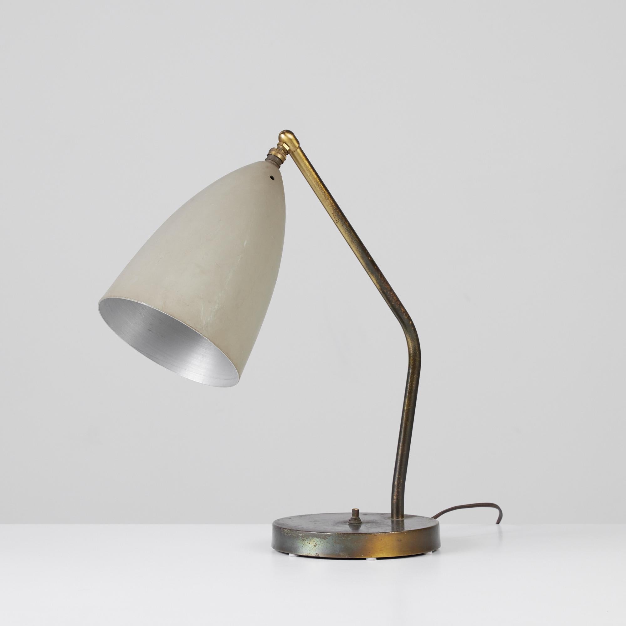 Designed by Swedish-American designer Greta Grossman for Ralph O. Smith, c.1950s, USA. The lamp, known as the grasshopper table lamp, offers a minimalist design with a patinated brass arm and base. The pebbled colored cone shaped spun aluminum shade