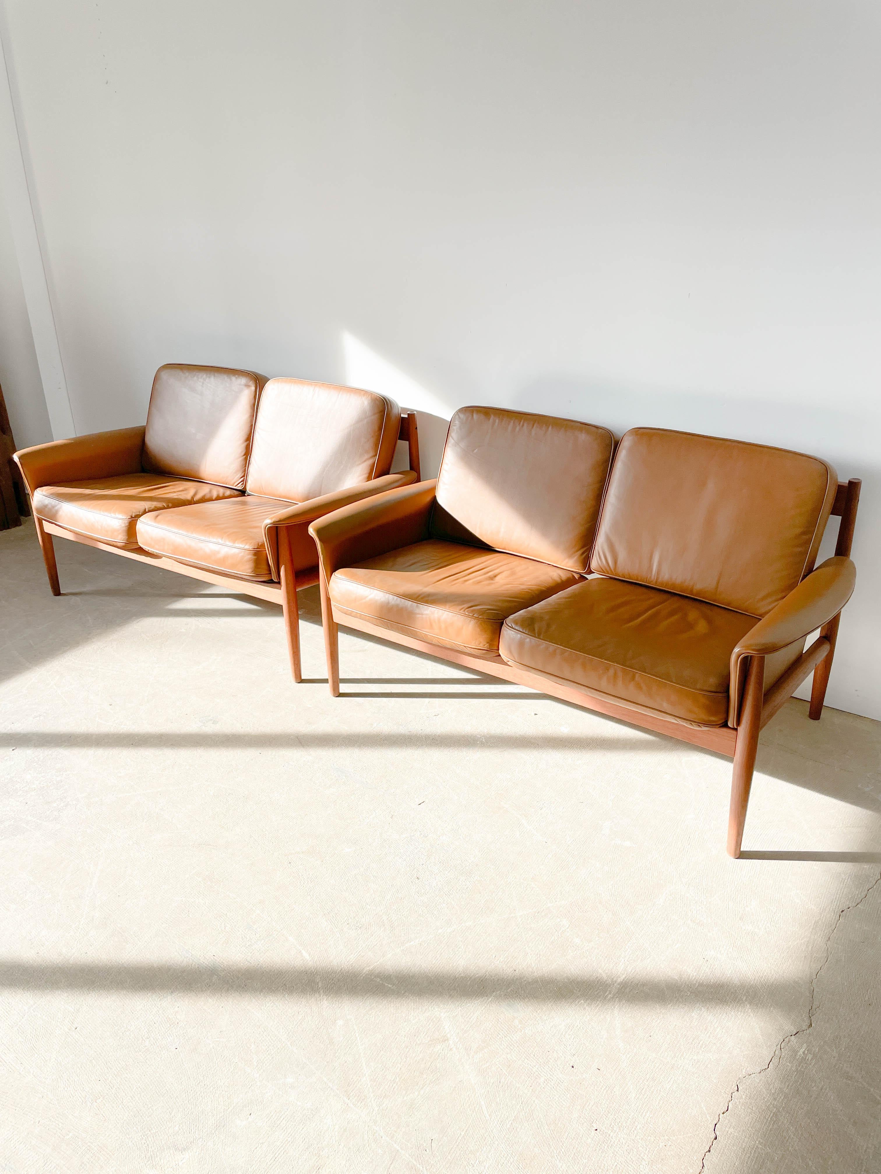 Luxurious teak frame and leather cushioned loveseats designed by Greta Jalk with Charles France for his company France and Sons in the 1950s. Gorgeous teak wood frame with elegant back staves all cleverly joined together and upholstered in a warm