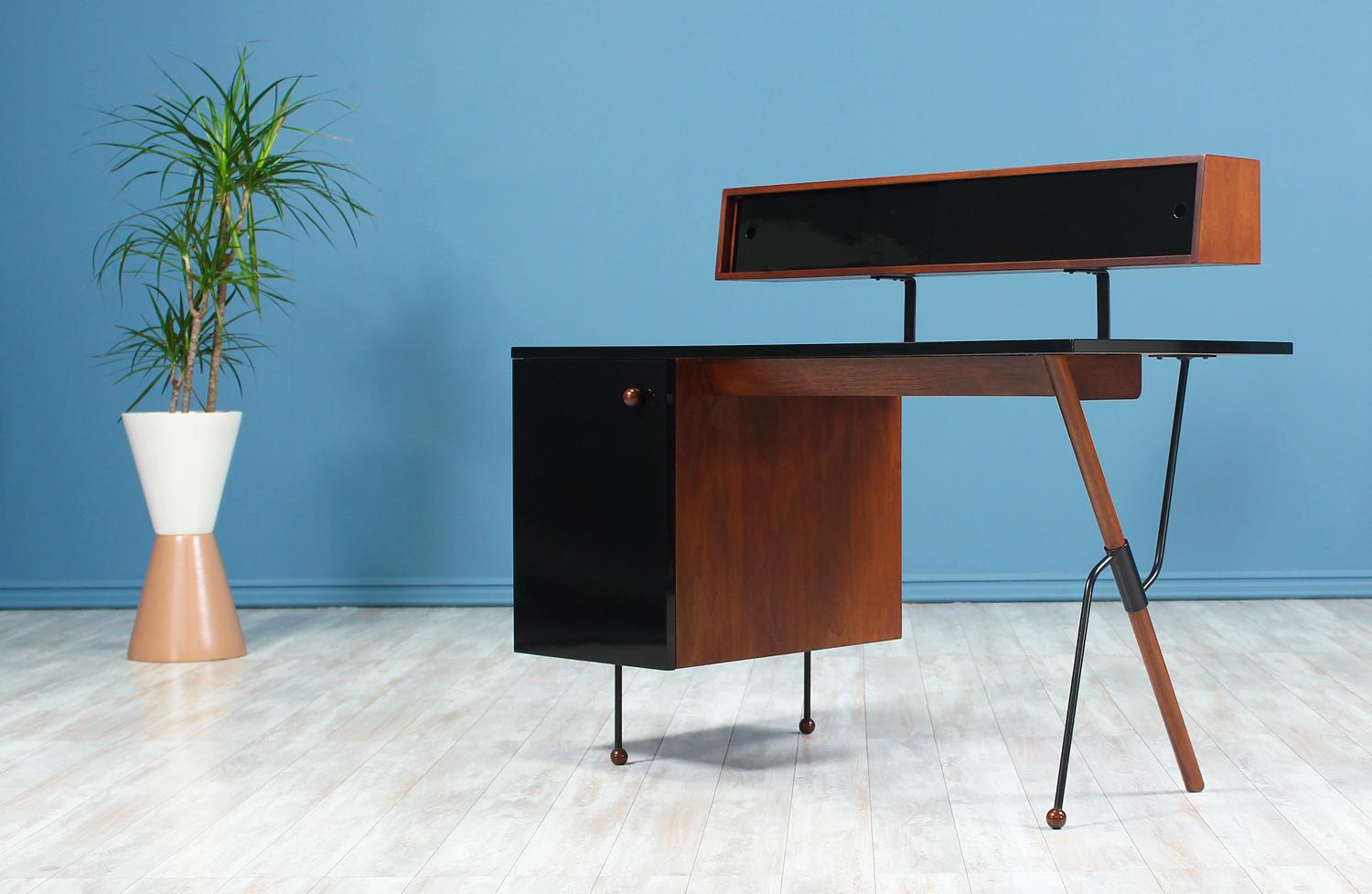 A fantastic Desk designed by Greta M. Grossman for Glenn of California in the United States in 1952. This beautiful desk features a walnut wood construction with a glossy black laminate coating which contrasts beautifully with the warm wood hue and