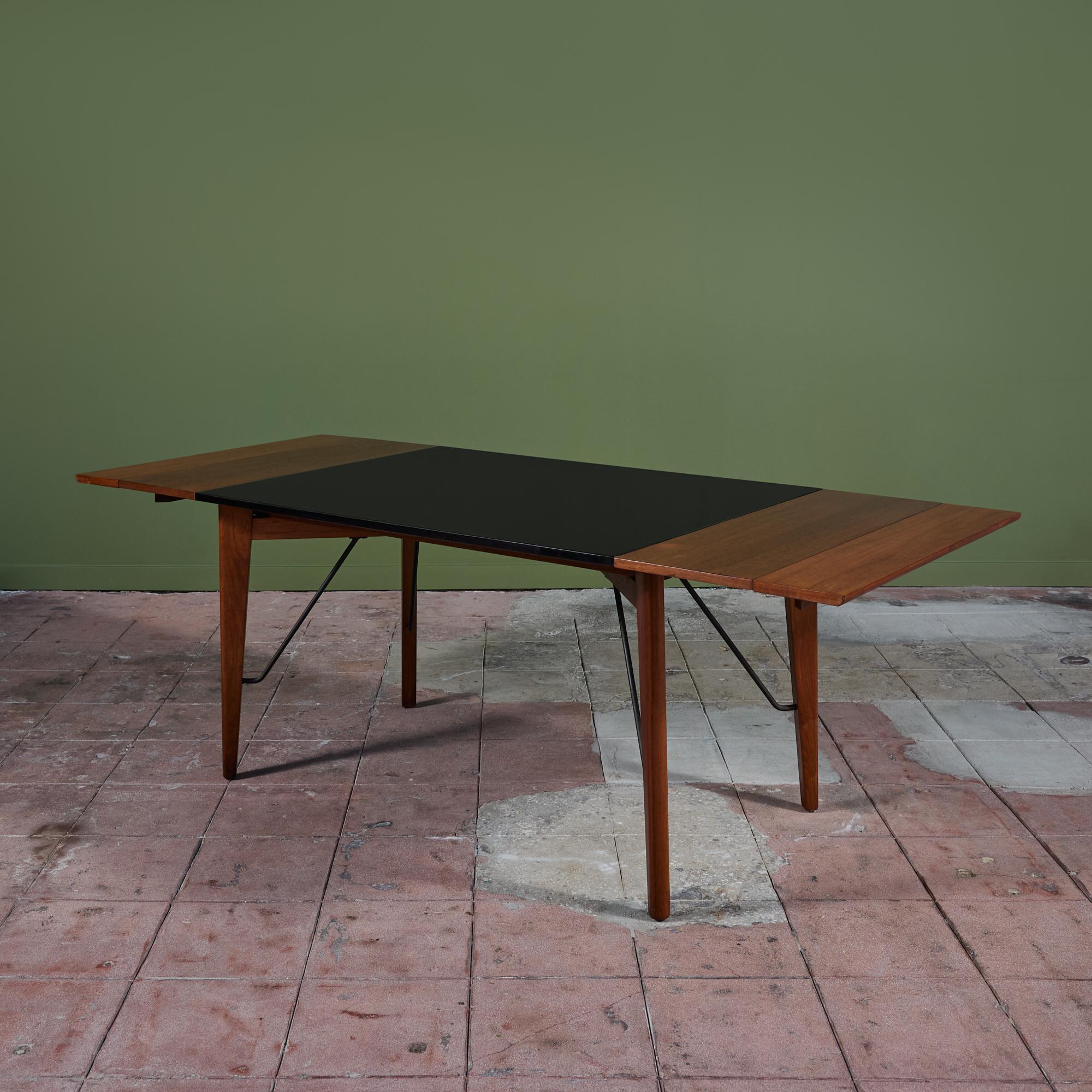 Rectangular dining table by Greta M. Grossman for Glenn of California, c. 1950s, USA. The table features a solid walnut wood frame with a black laminate top and iron hardware. The expandable table has two removable leaves, allowing it to expand up