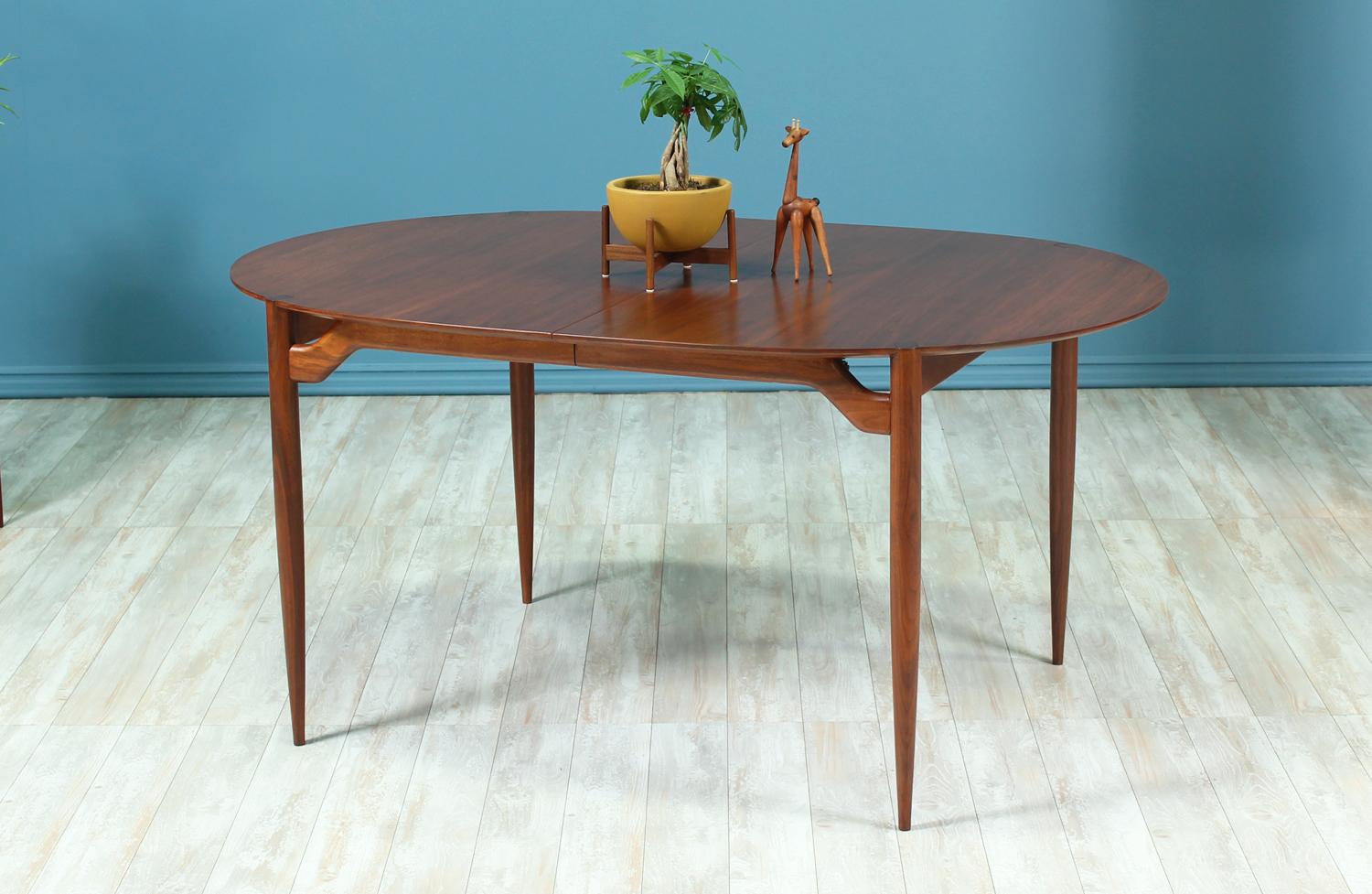 Dining table designed by Greta M. Grossman for Glenn of California in the United States circa 1950’s. This stunning table is made of walnut wood and features four tapered legs with sculpted stretchers that support the top while creating a floating