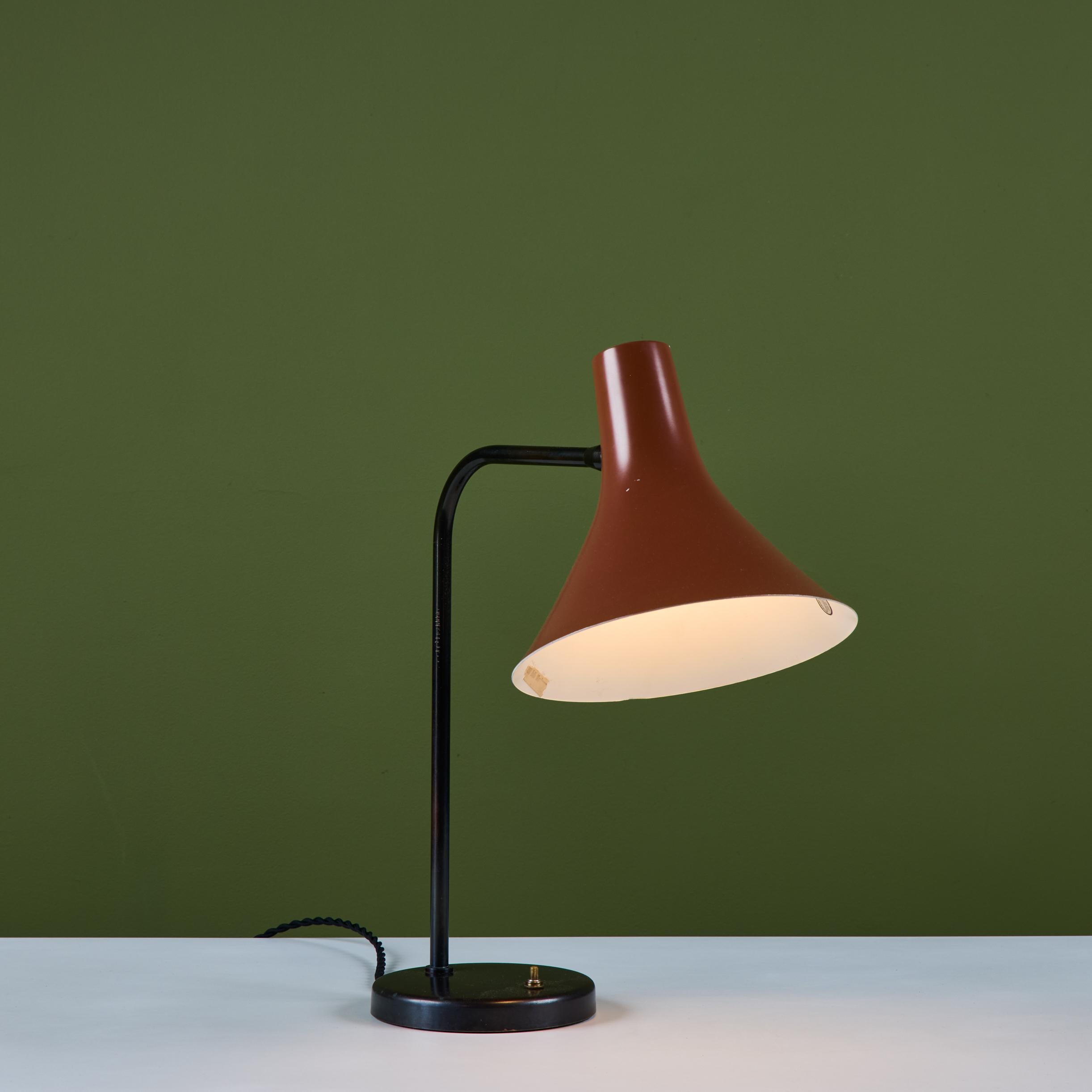 Lámpara de escritorio, diseñada por Greta Von Nessen para Nessen Studios c.1960s, EEUU. La lámpara presenta una pantalla de trompeta esmaltada en naranja quemado totalmente articulada, con un pie curvo de acero esmaltado en negro y una base redonda.
