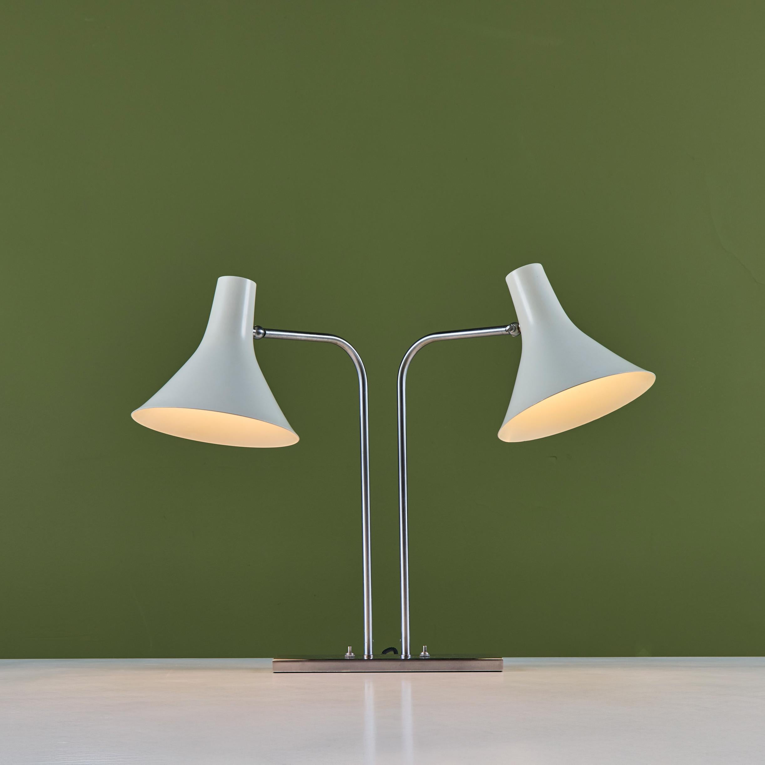 Double shade desk lamp designed by Greta von Nessen c.1960s, USA, for Nessen Studios. The lamp features two white enameled trumpet shades that pivot up and down, with curved steel arms that rotate left and right 90 degrees, set on a rectangular