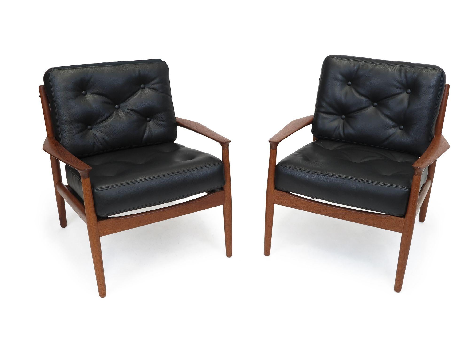 Pair of Danish Modern teak lounge chairs designed by Grete Jalk for Glostrup Mobelfabrik, model 218. Crafted of solid teak frames with sculpted arms newly upholstered in soft black leather with button tufting.
Measurements: 
W 28.75 x D 27.75 x H